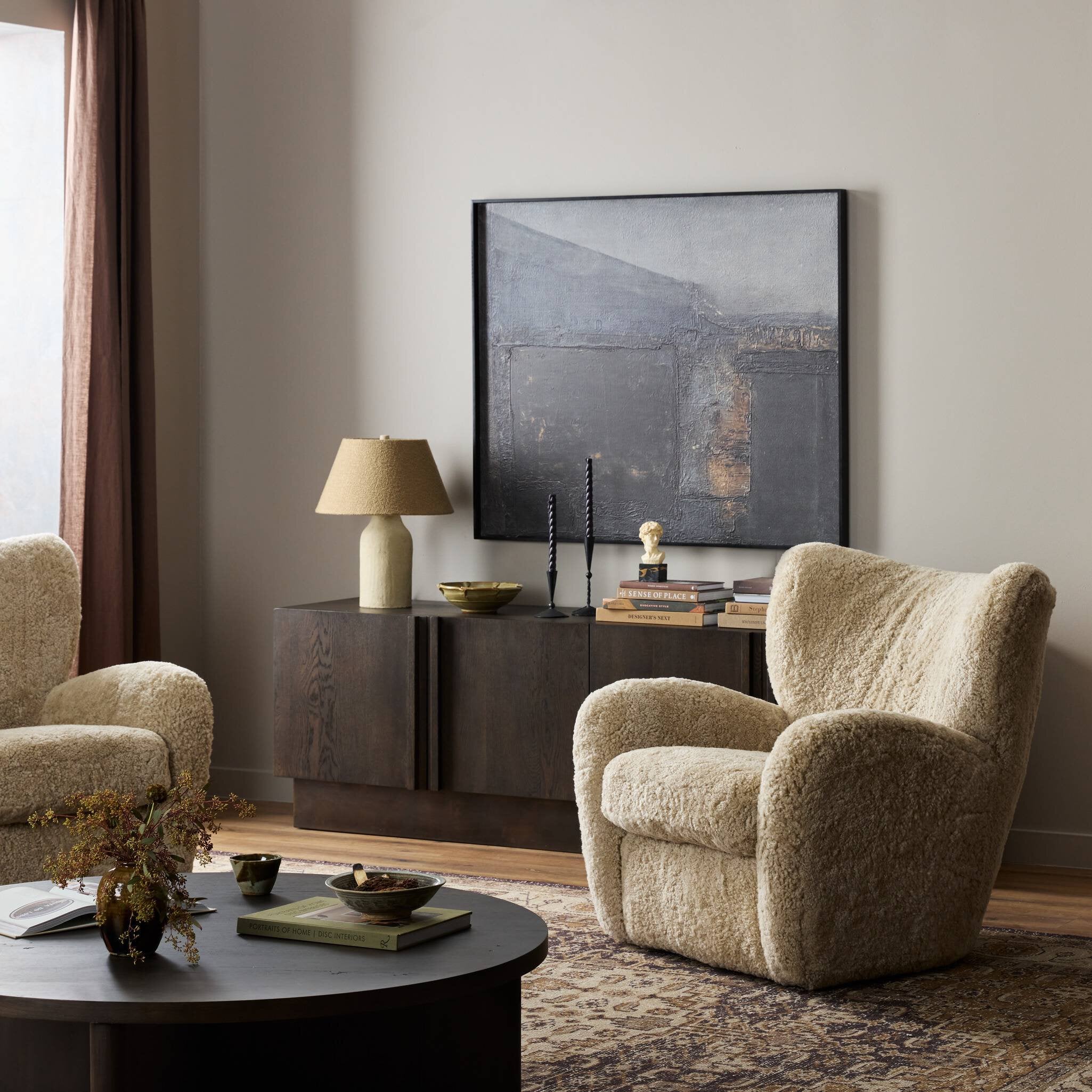 Modern living room with beige armchairs, a dark coffee table, and a sideboard.