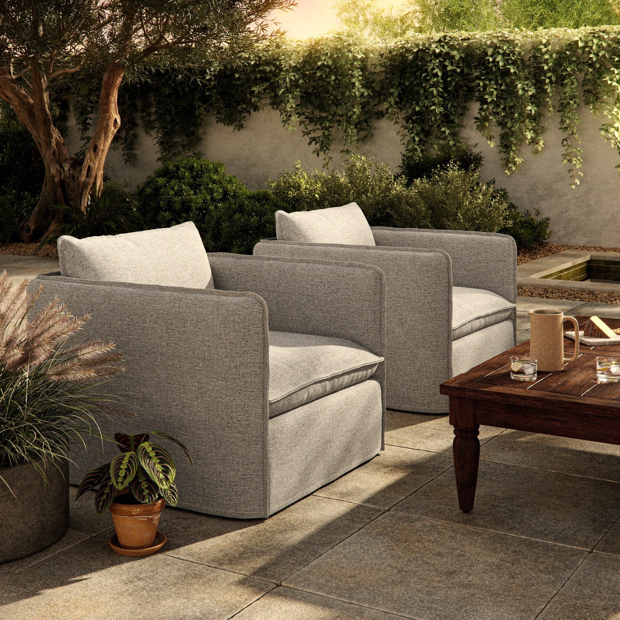 Outdoor patio setting with gray swivel armchairs and a wooden coffee table.