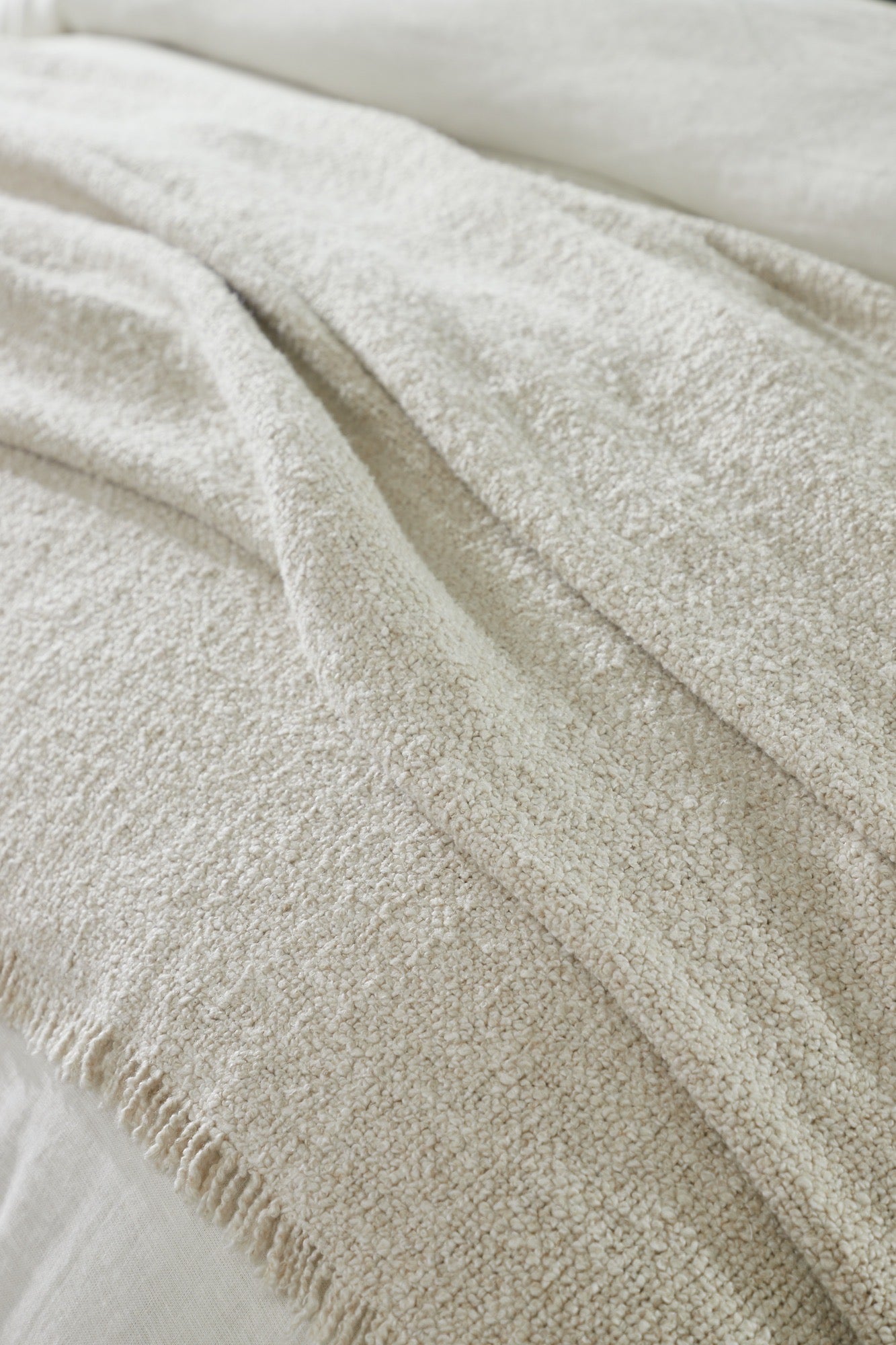 Stacked cream coverlet and shams showcasing their boucle weave and natural softness.