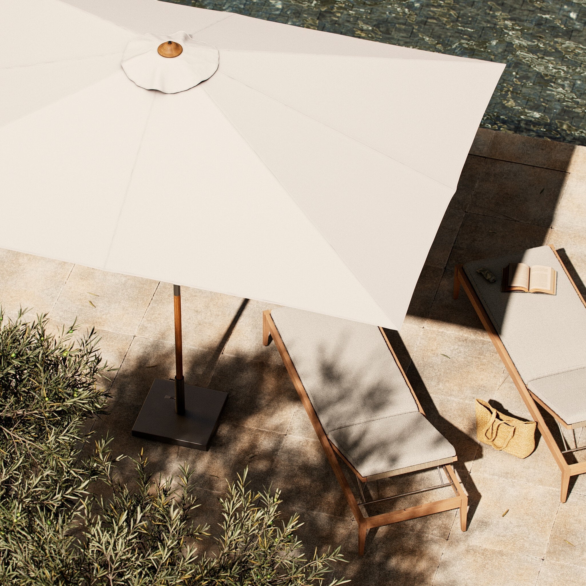 Beige outdoor umbrella and chairs on a stone patio with plants.