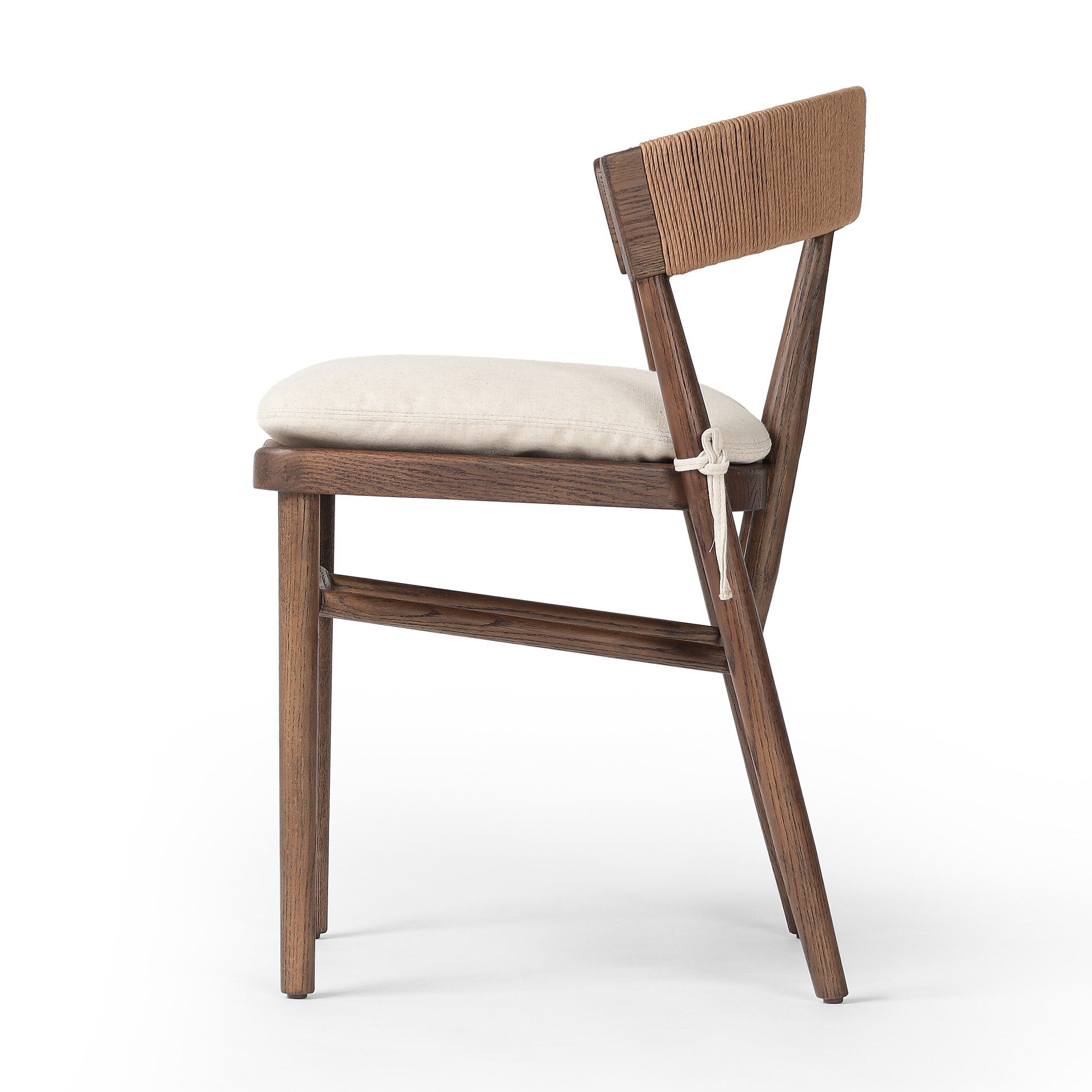 Side profile of a solid oak dining chair with tapered legs, a woven backrest, and natural color seat cushion on a white background.