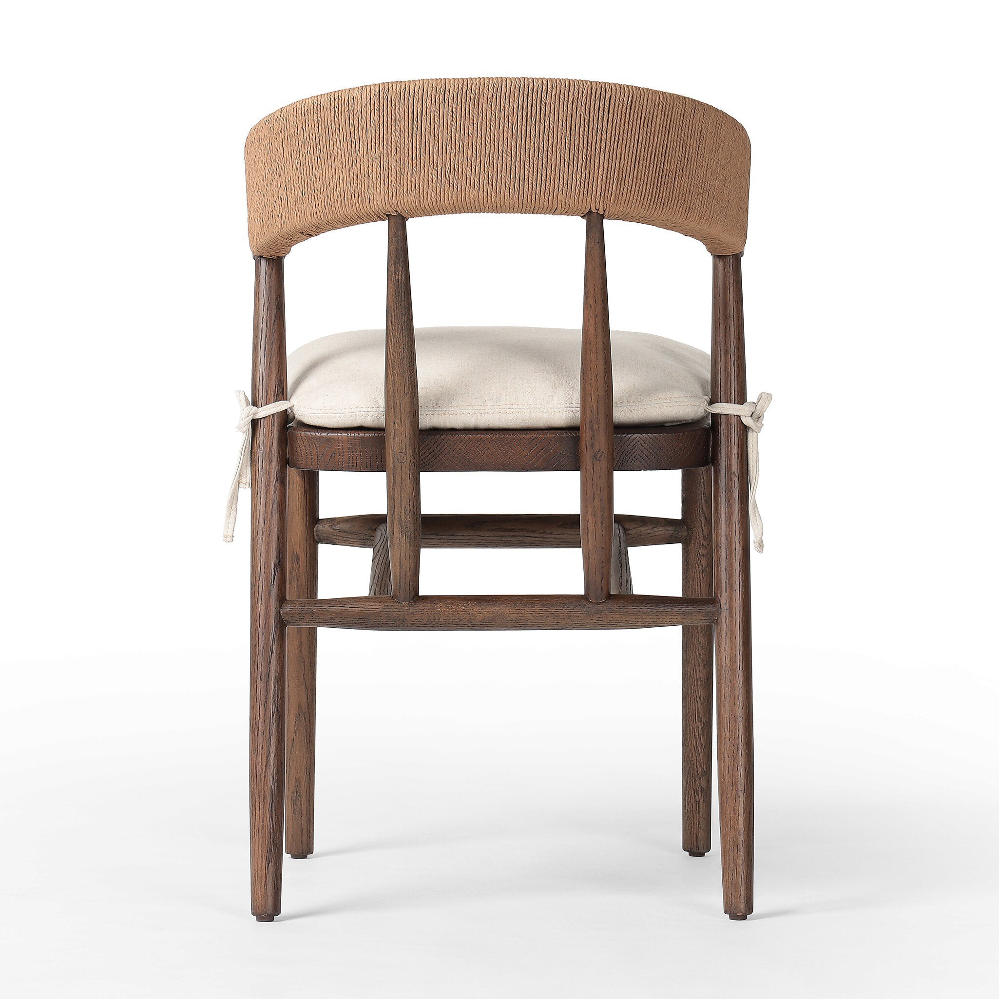 The back of a solid oak dining chair with tapered legs, a woven backrest, and natural color seat cushion on a white background.