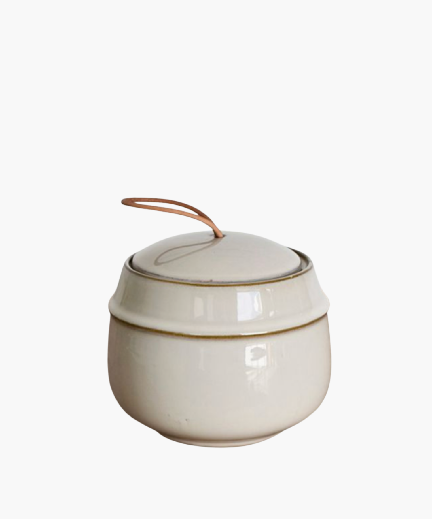 Elegant cream-colored ceramic jar with a lid, featuring a simple, rustic design. A leather loop handle adds a touch of warmth and charm.