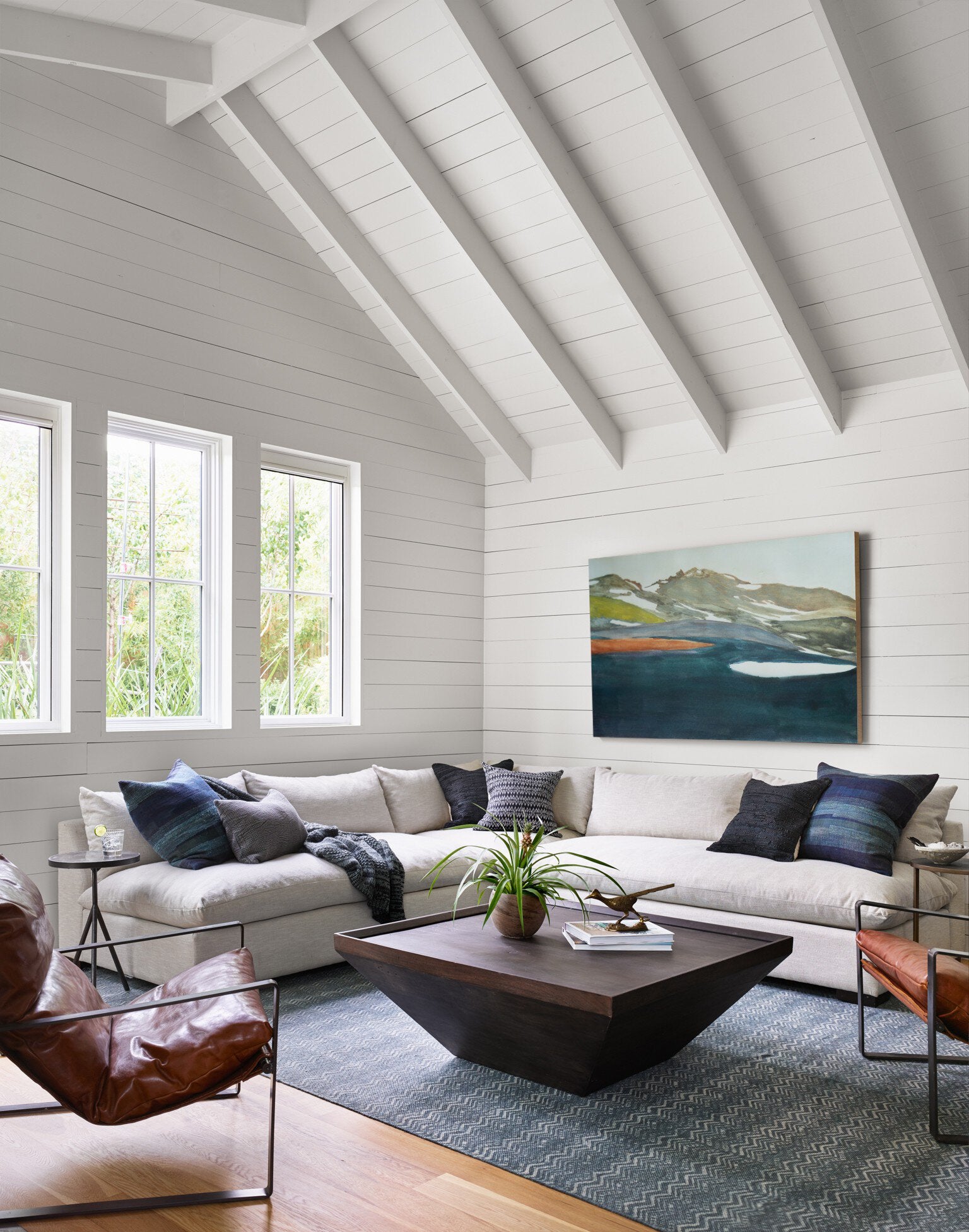 Modern living room with white walls, wooden floor, and a sectional sofa.