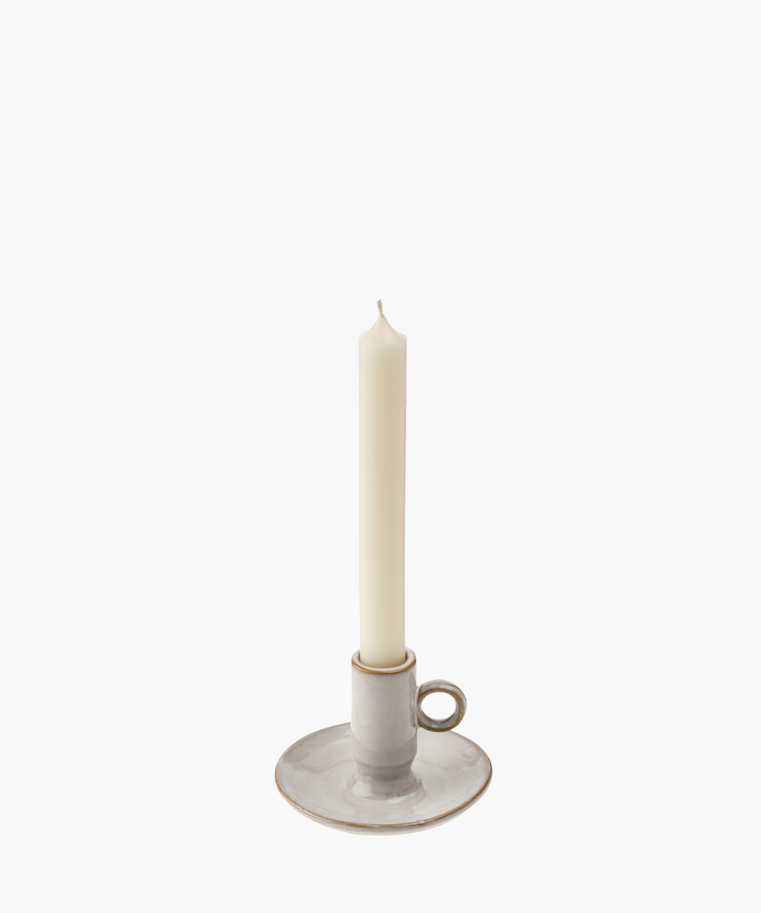 A tall, unlit white candle stands in a simple, round ceramic holder with a loop handle, against a white background, suggesting elegance and simplicity.