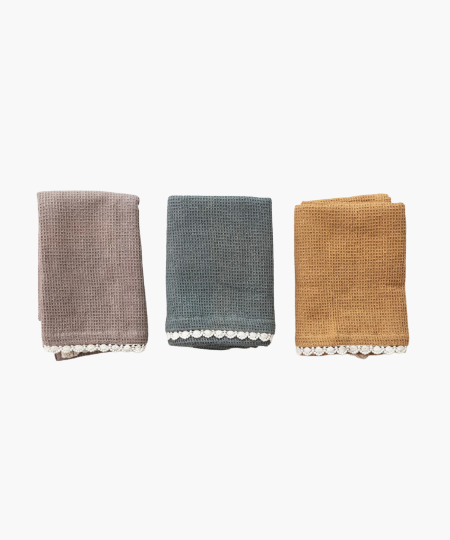 Three folded waffle-knit towels in taupe, teal, and mustard are lined side by side. Each towel features a delicate white lace trim along the edge.
