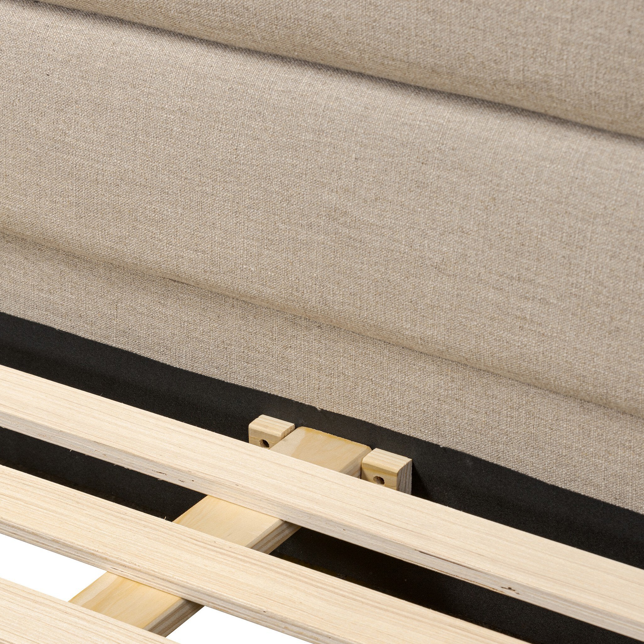 Close up of a taupe upholstered bed with horizontal channeling on the headboard and white bedding on a white background.