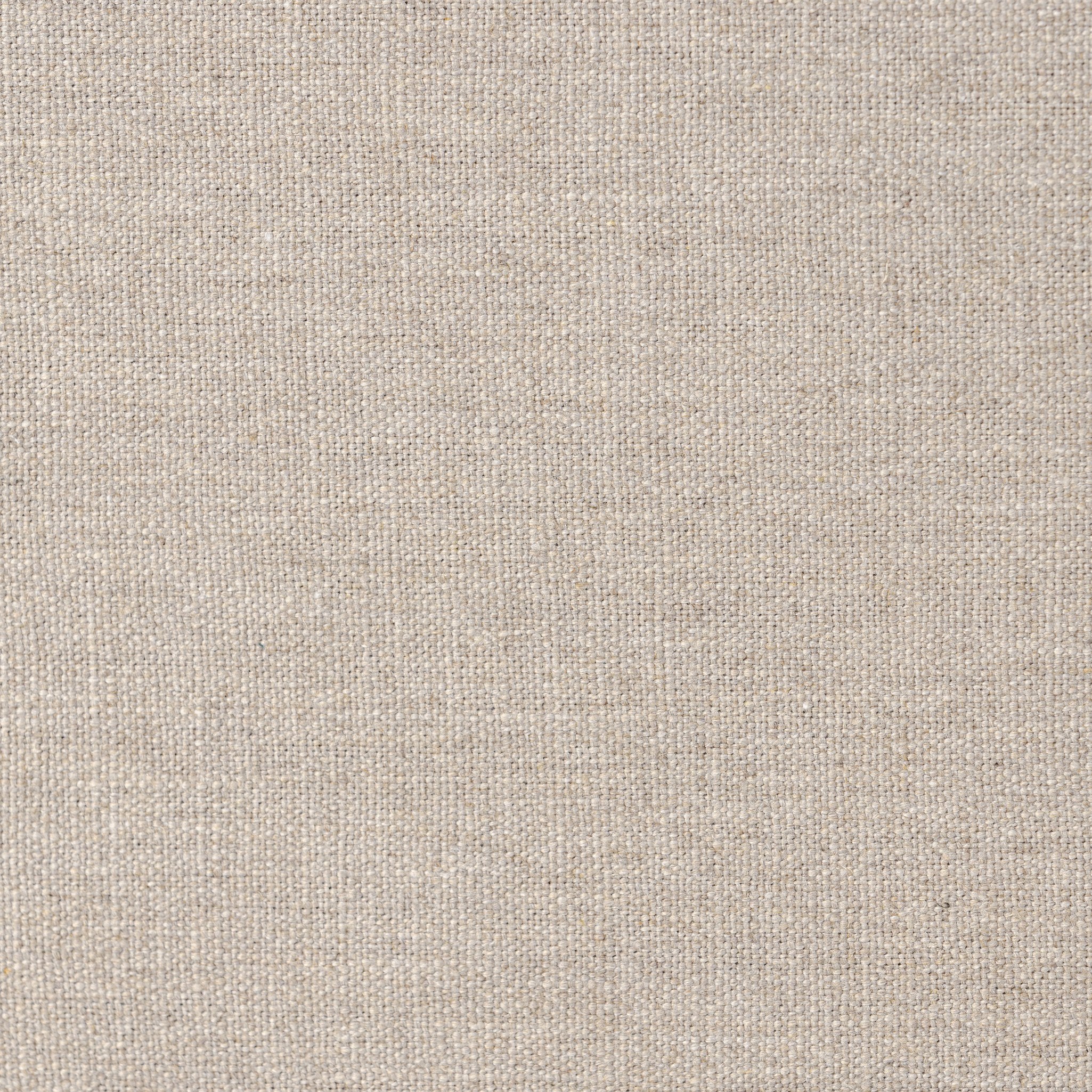 Close up of a taupe upholstered bed with horizontal channeling on the headboard and white bedding on a white background.