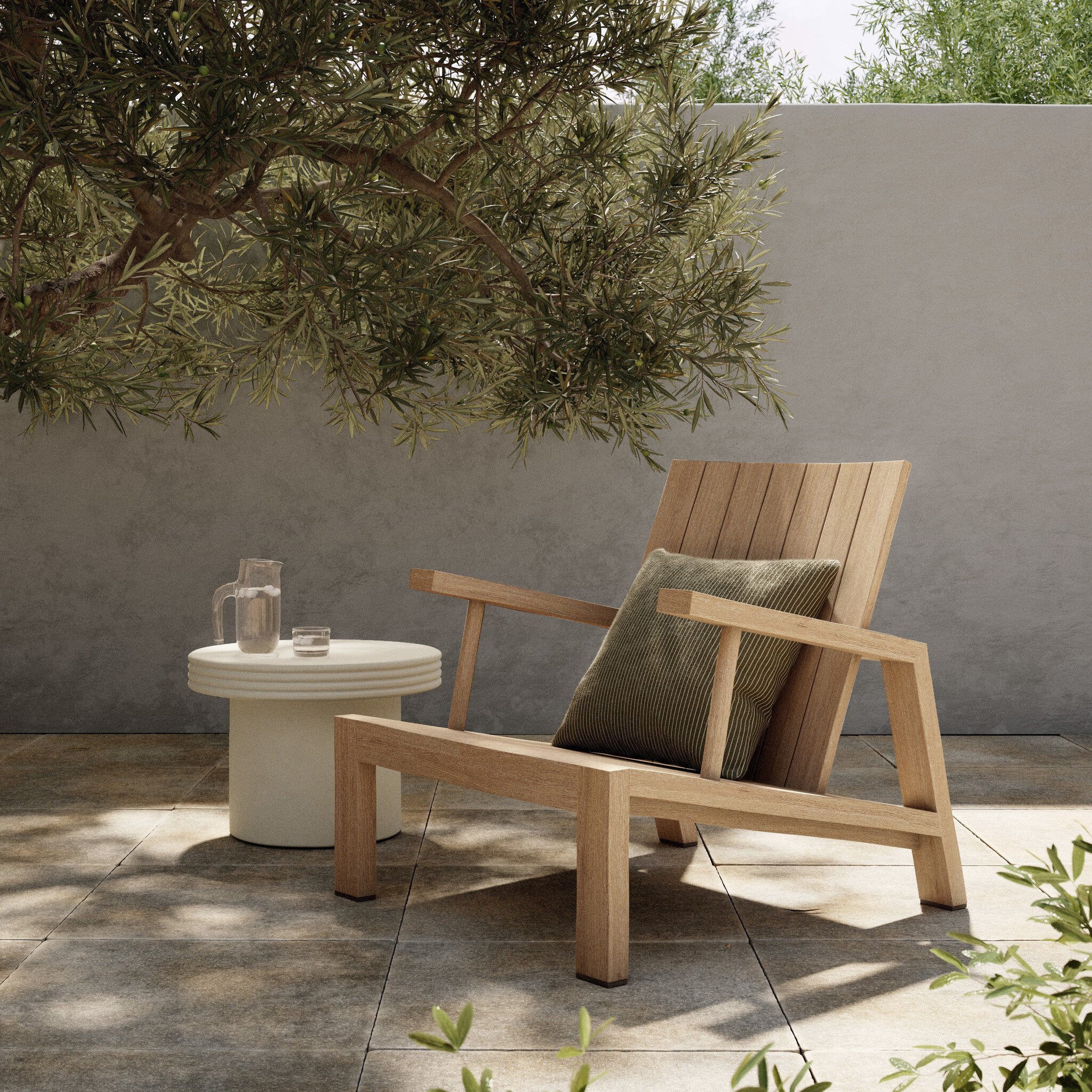 Wooden outdoor chair with a cushion on a patio with a small table and plants.