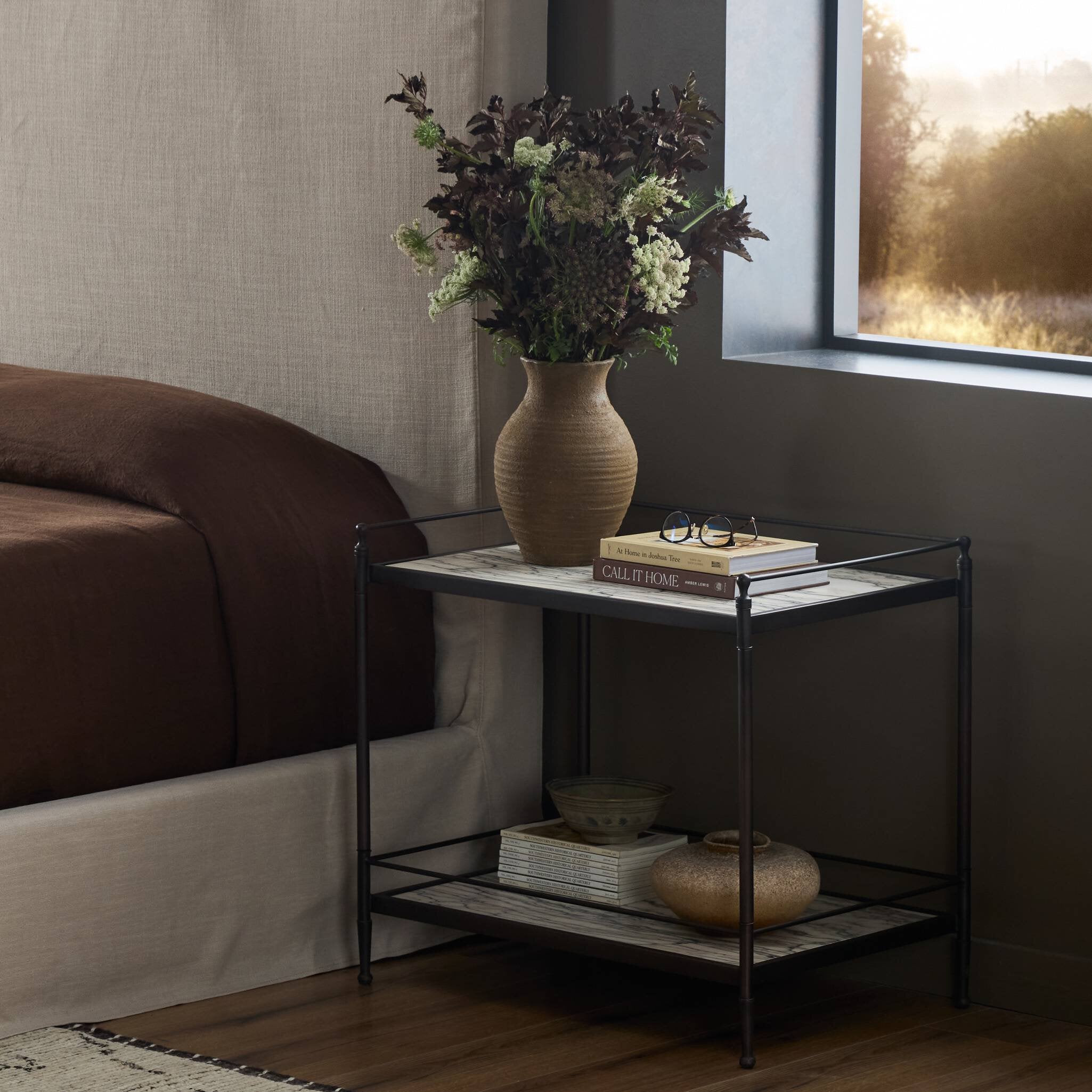 Bedroom with a nightstand featuring a vase with flowers and books.