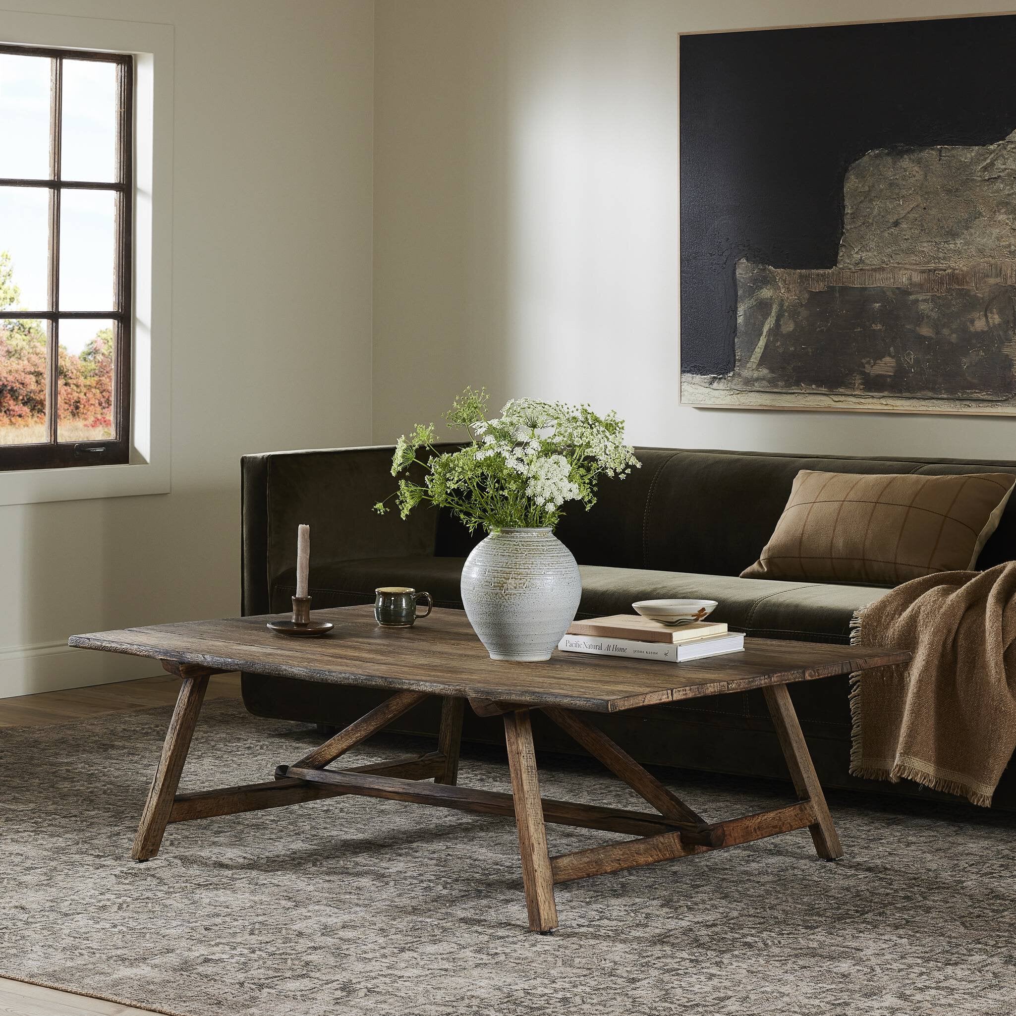 Living room with a wooden coffee table, vase with flowers, and books.