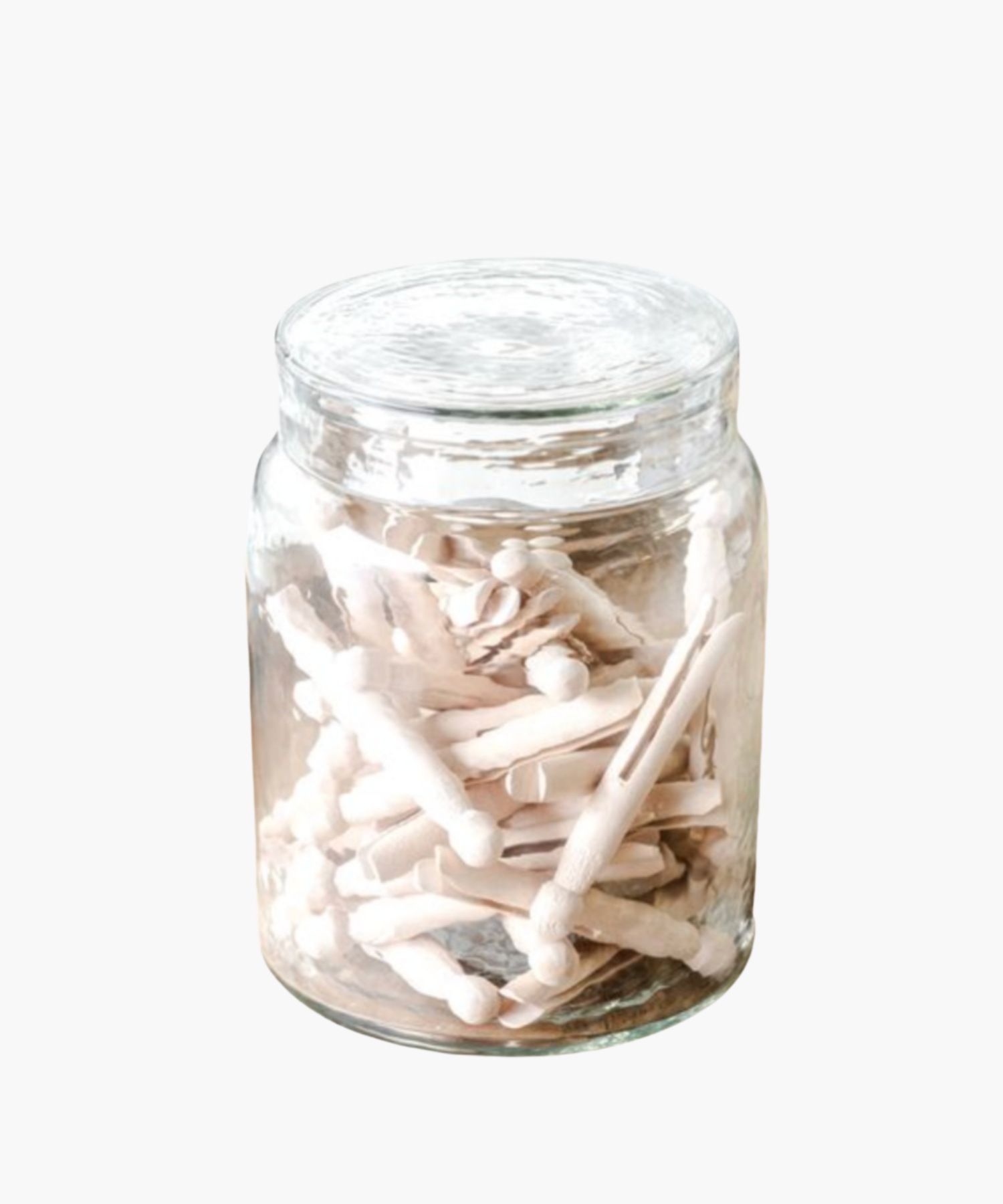 A clear glass jar filled with light-colored wooden clothespins against a white background. The scene conveys simplicity and vintage charm.