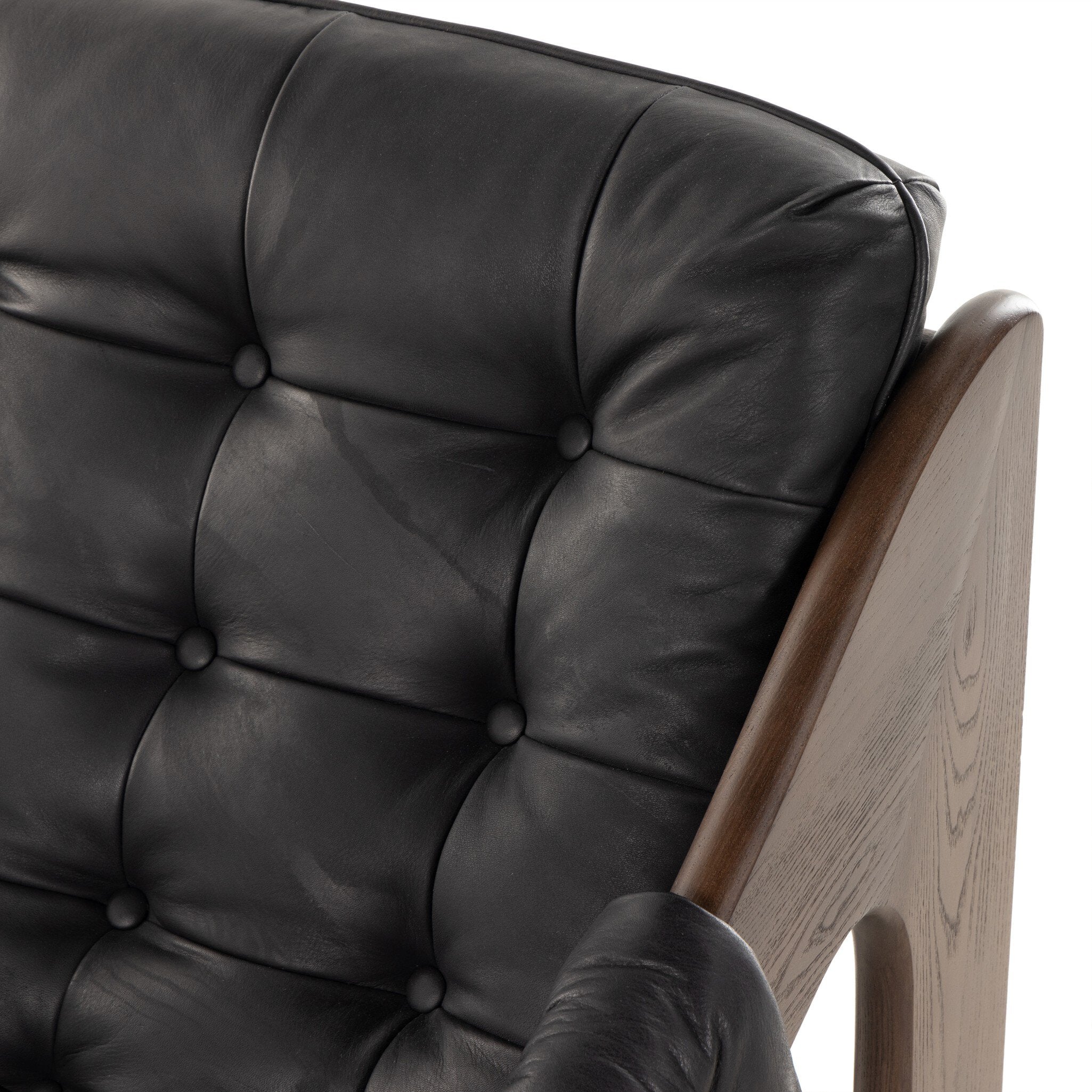 Tufted black leather sling style armchair with wooden frame on a white background.