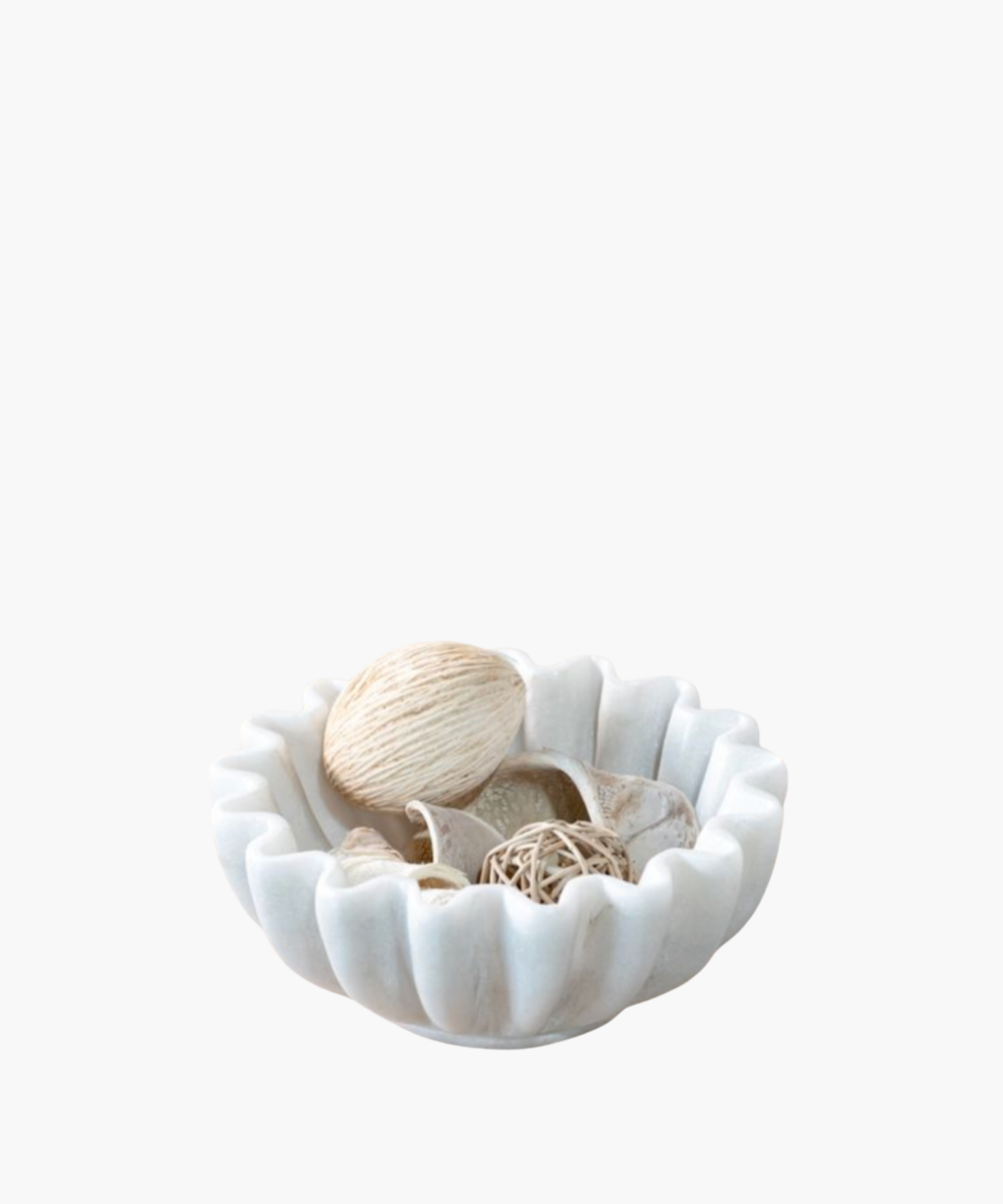 A scalloped cream ceramic bowl holds natural decorative items, including a string-wrapped ball, rattan orb, and seashells, conveying a calm, coastal vibe.