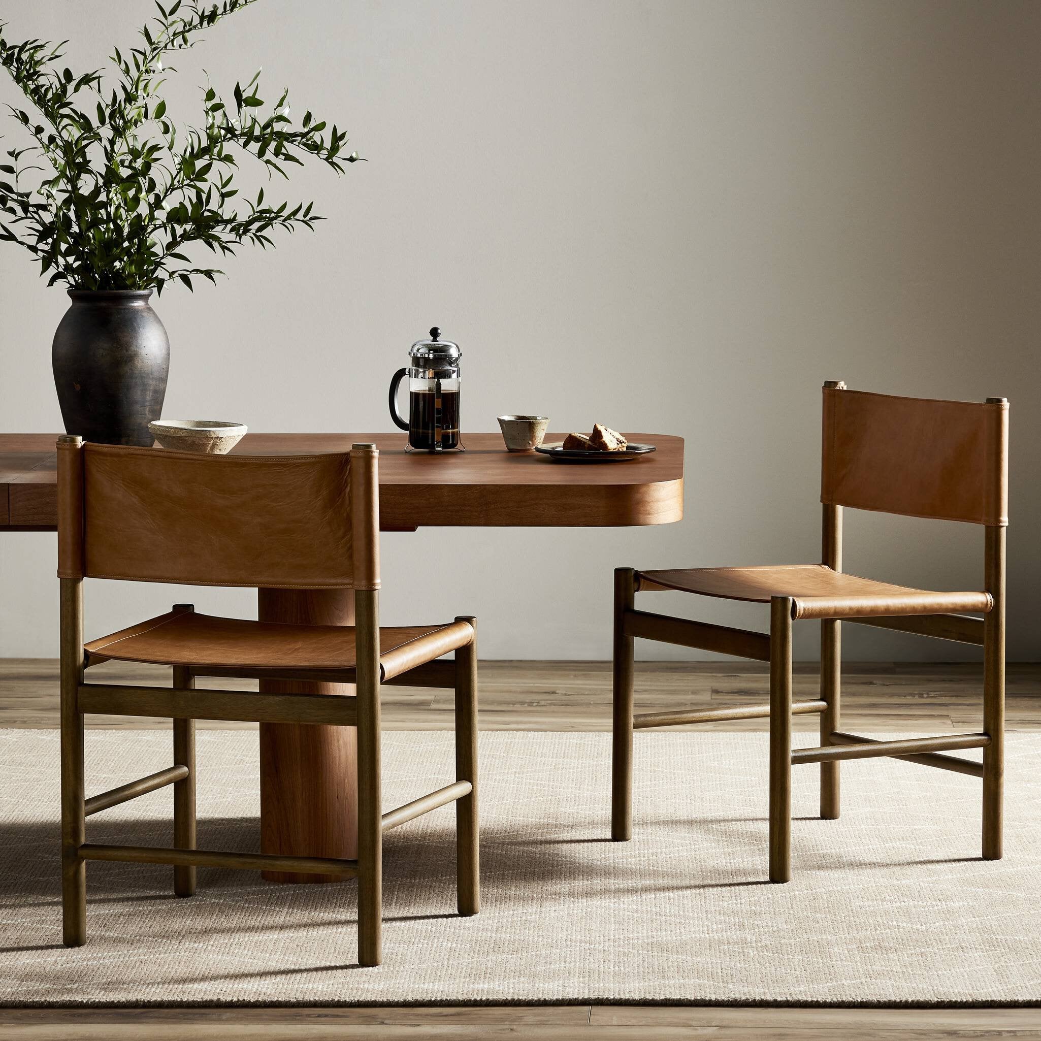 Dining table with dining chairs and a vase of plants in a room.
