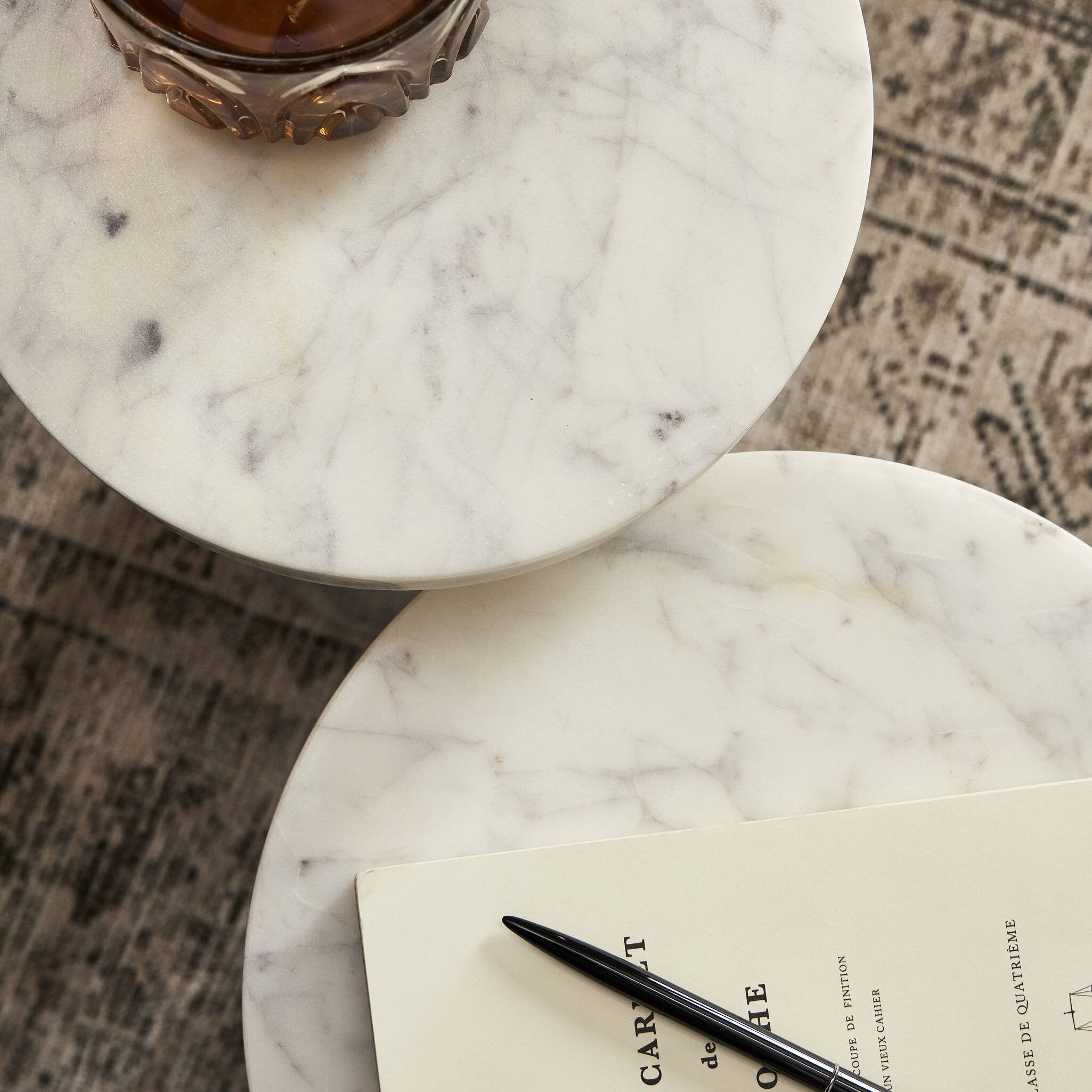 Marble nest tables styled with a glass of whiskey and a book. 