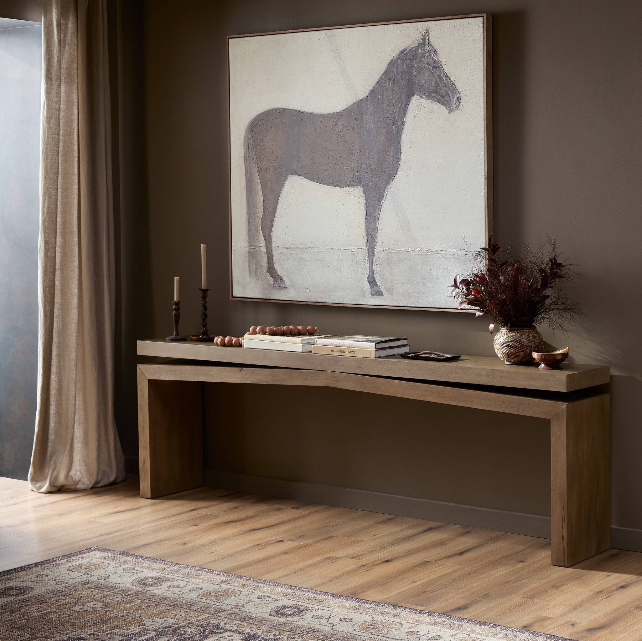 Wooden console table with decorative items against a wall with a horse painting.