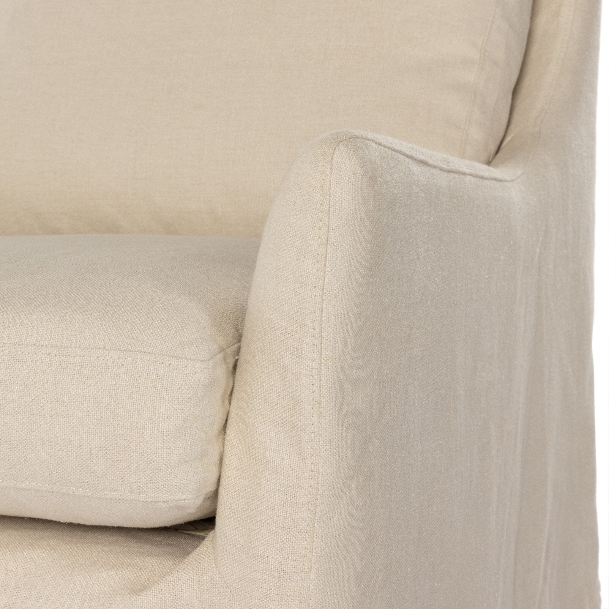 Close up of a traditional swivel chair with an ivory slipcover on a white background. 