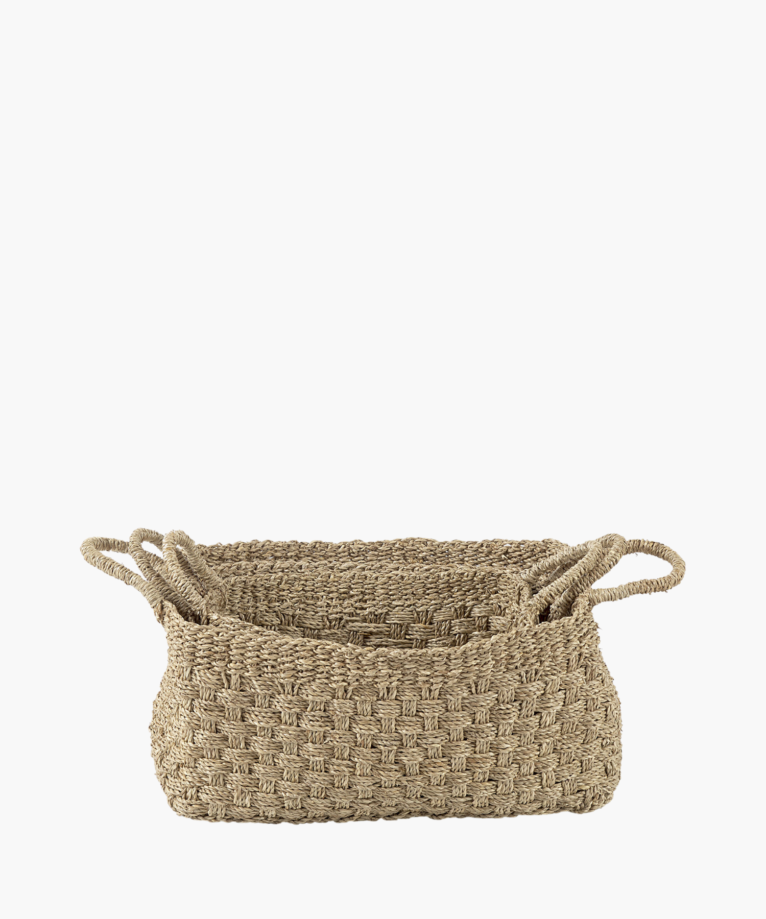 Three rectangular seagrass woven baskets in various sizes with two looped handles, made of natural fibers in a textured, checkerboard pattern. The tone is earthy and rustic.
