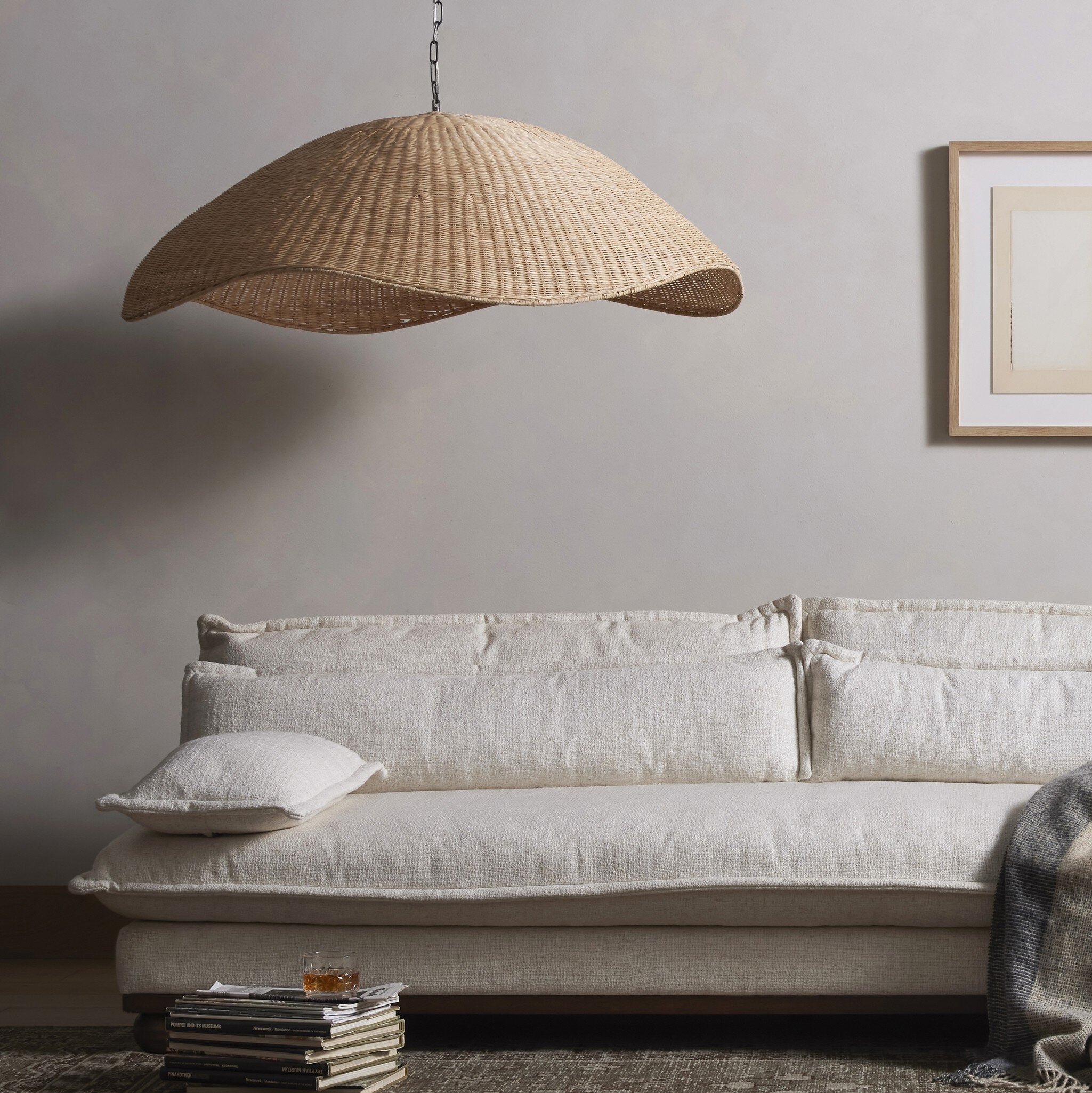 Woven pendant light hanging above a beige sofa in a living room setting.