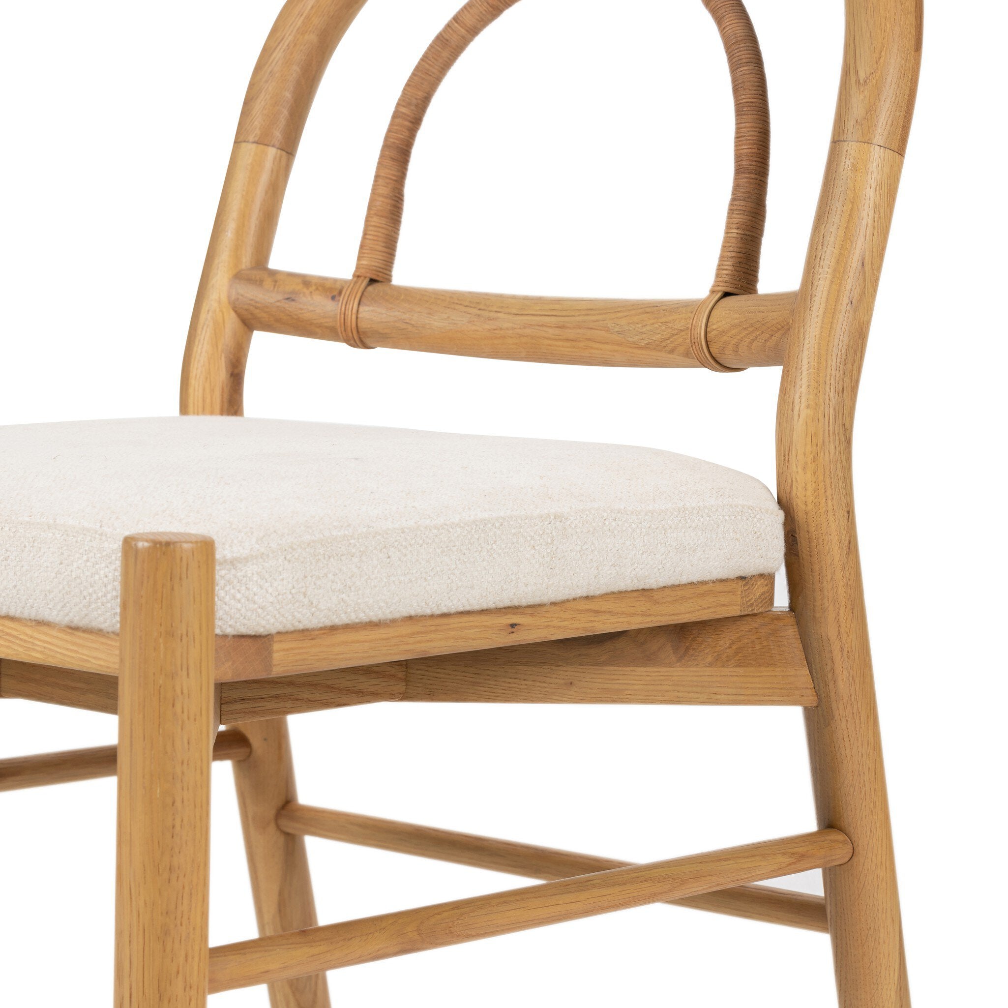 A solid oak dining chair with an arched frame, hand-wrapped cane back detailing, and an upholstered drop-in seat. 