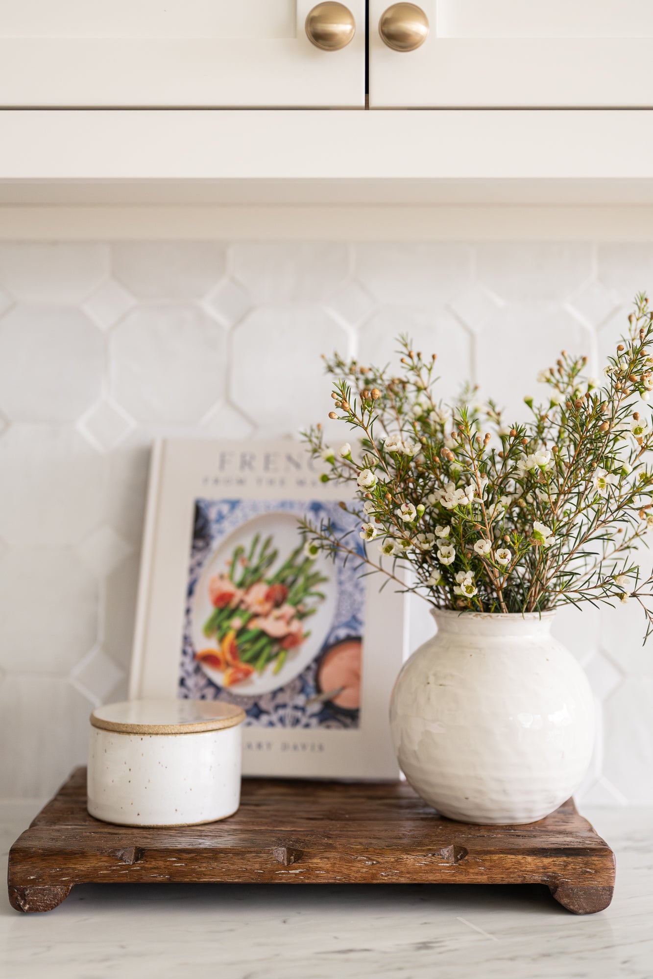 Round ceramic vase with a textured white glaze styled with florals and kitchen essentials. 