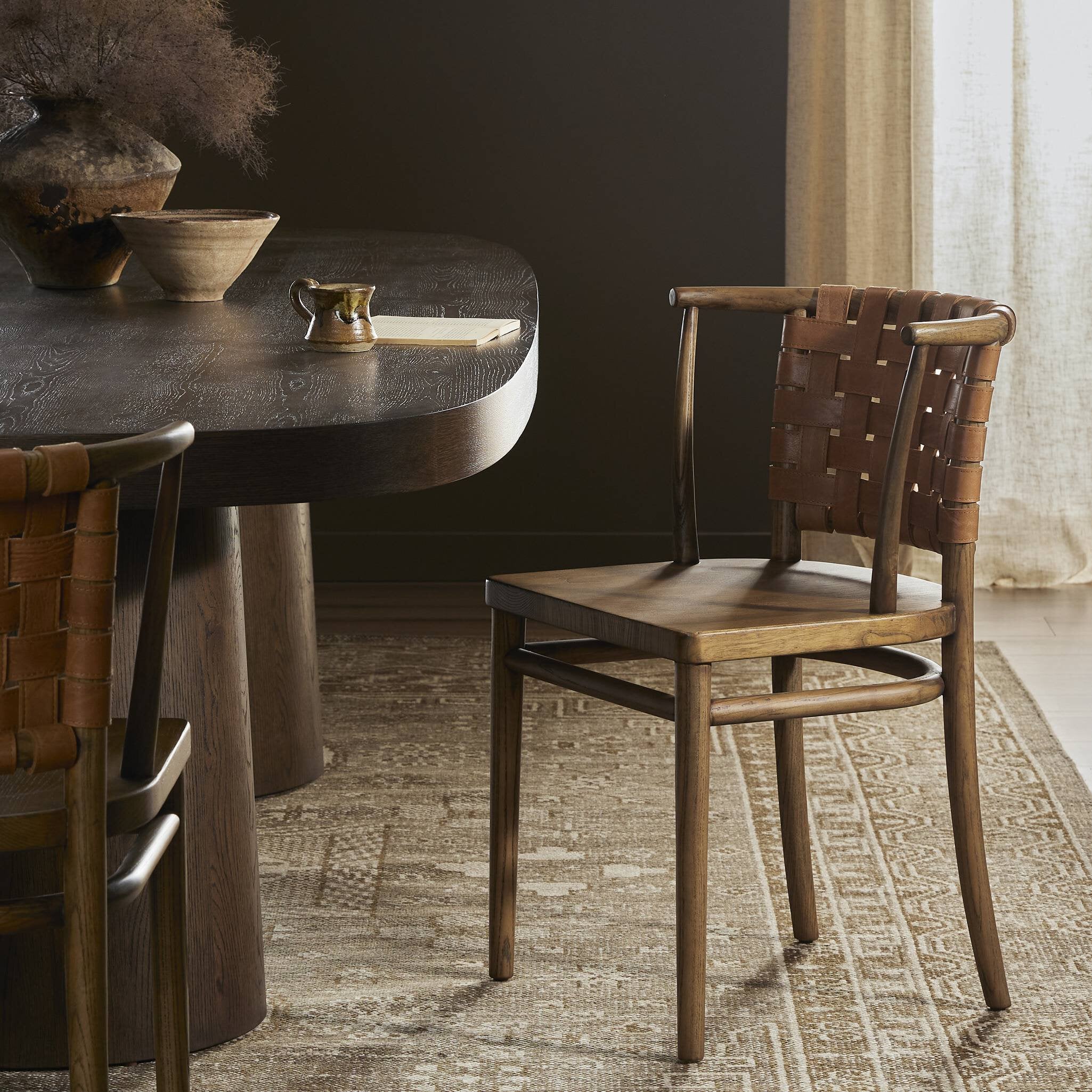 Dining table with woven back chairs on a textured rug