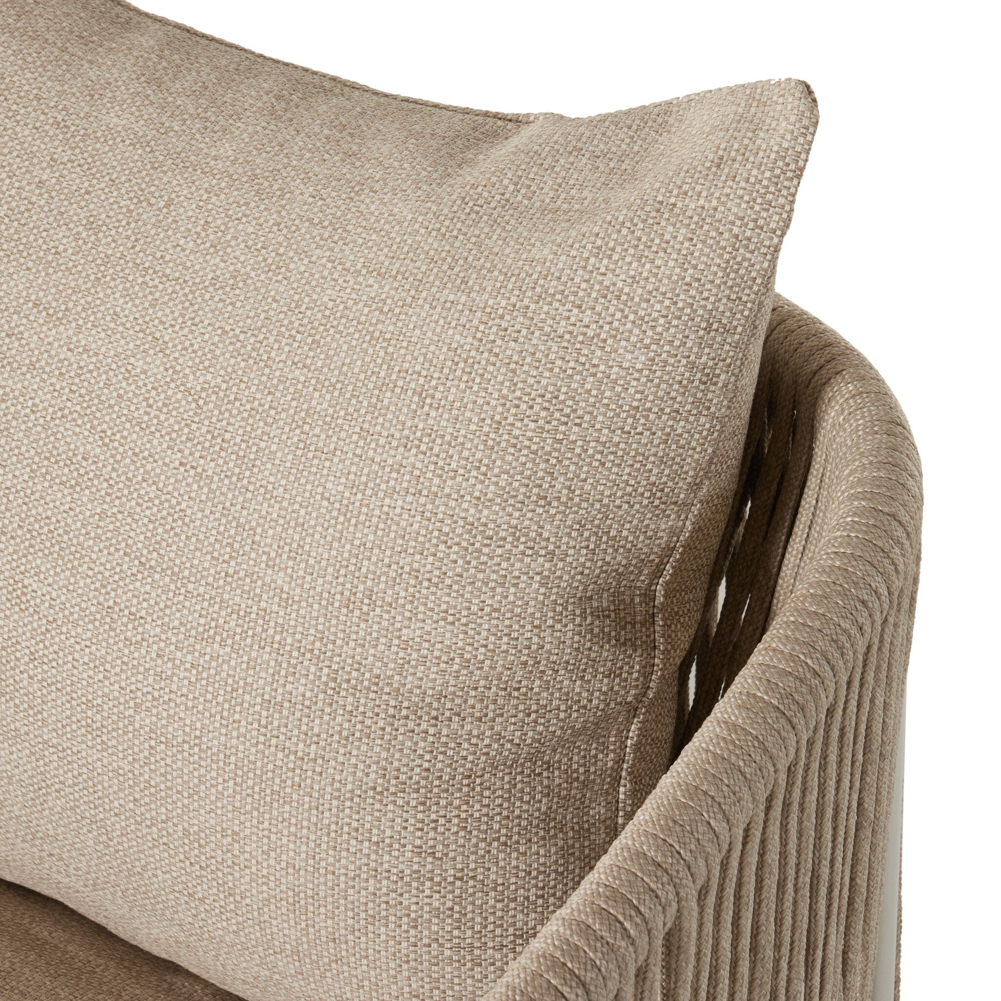 A close up view of a rope based-designed swivel chair in a sand color with a wide cushion and throw pillow on a white background. 