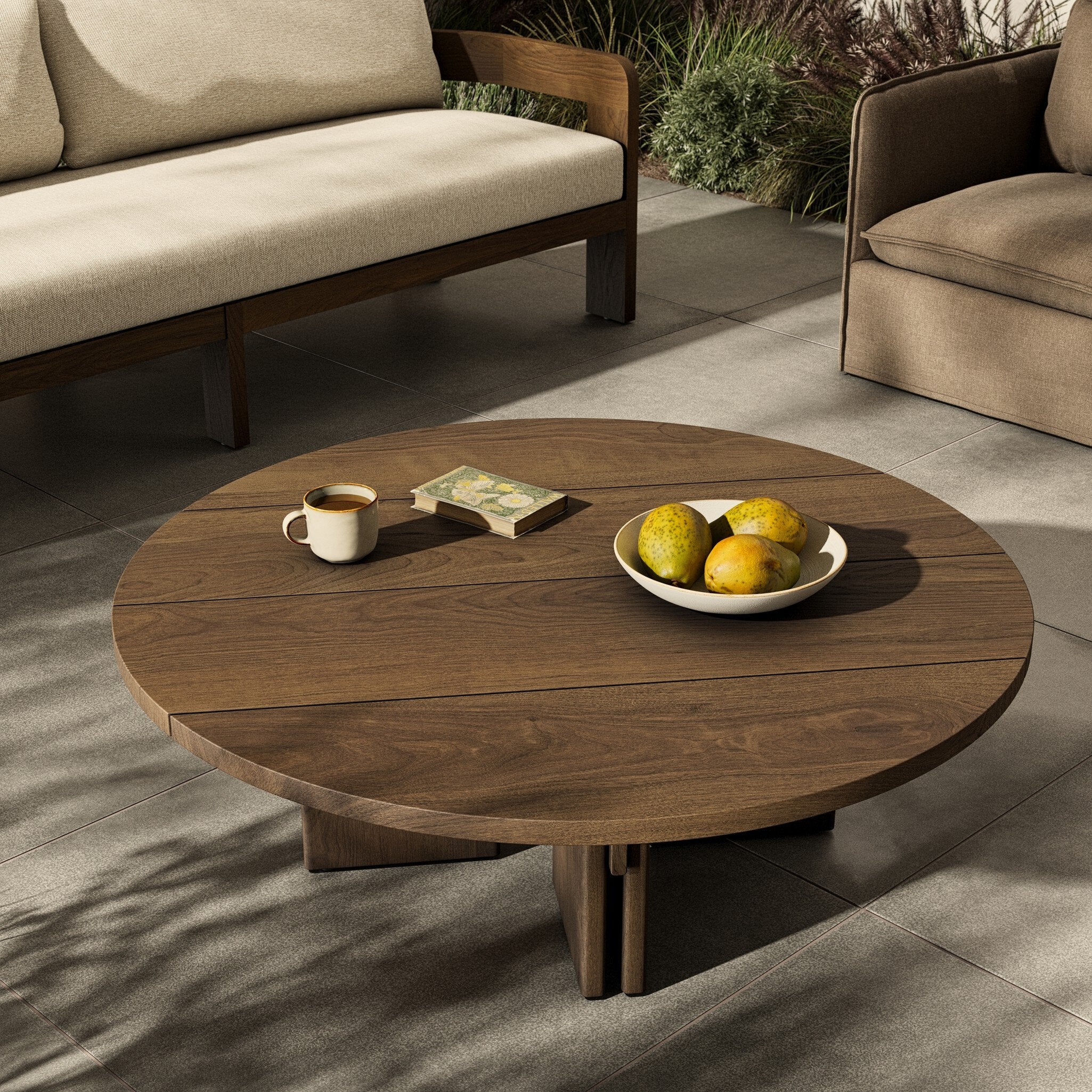 Round wooden coffee table with a cup and fruit on a patio setting