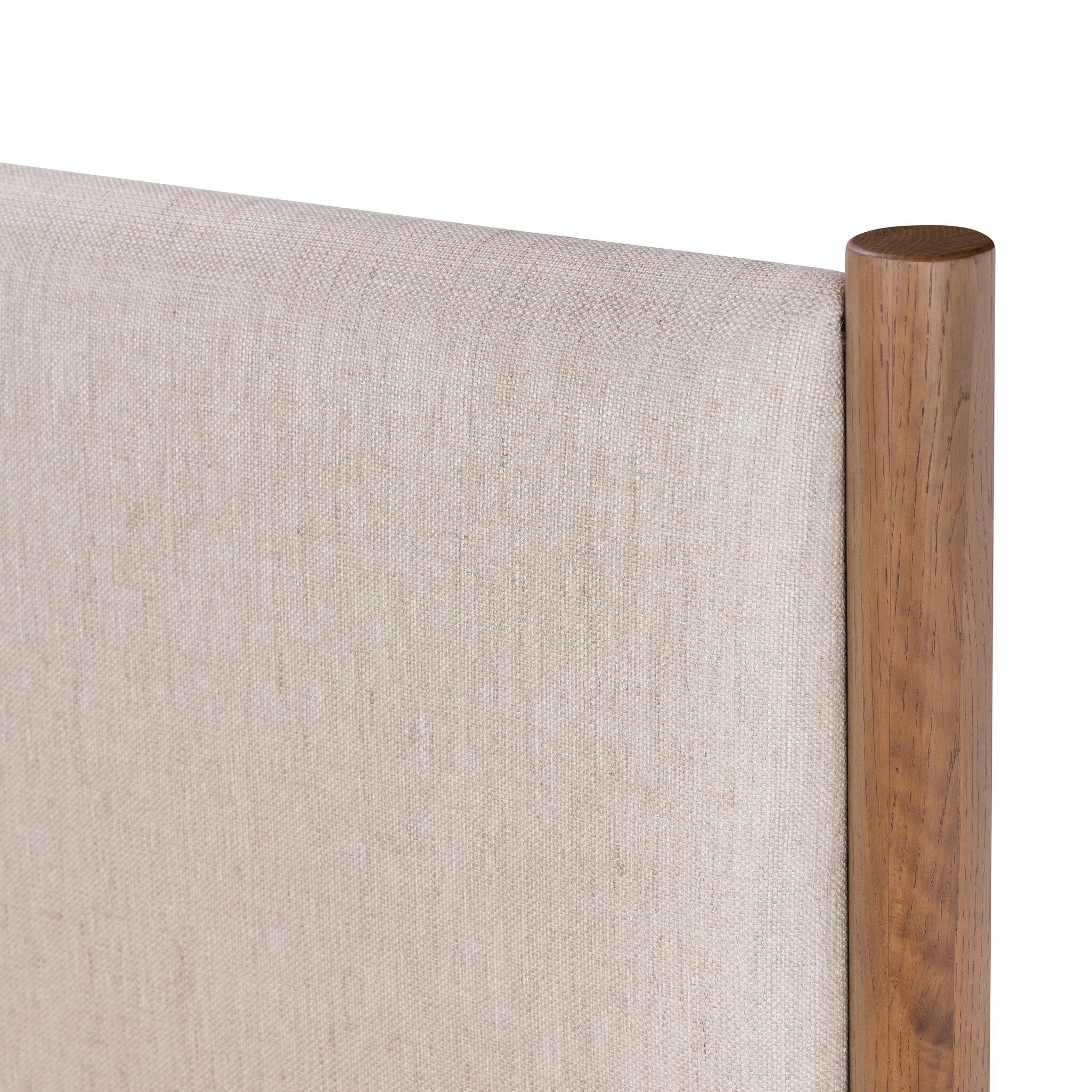 Close up of a wooden bed with upholstered headboard and white bedding on a white background.