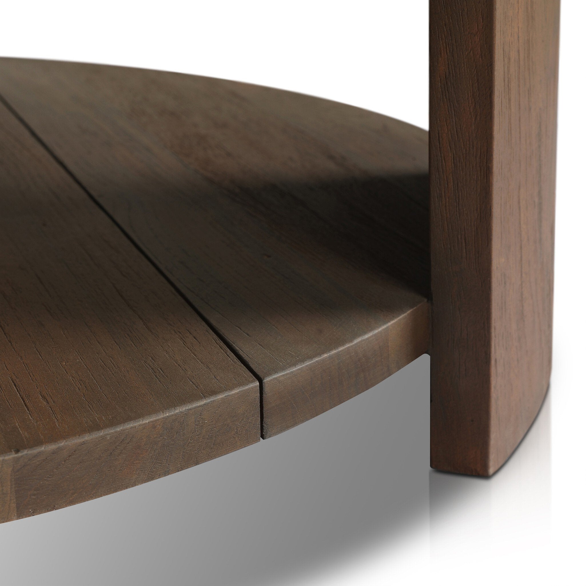 Close up of the lower shelf from the two tiered round coffee table made from reclaimed wood with chunky legs and a brown finish.