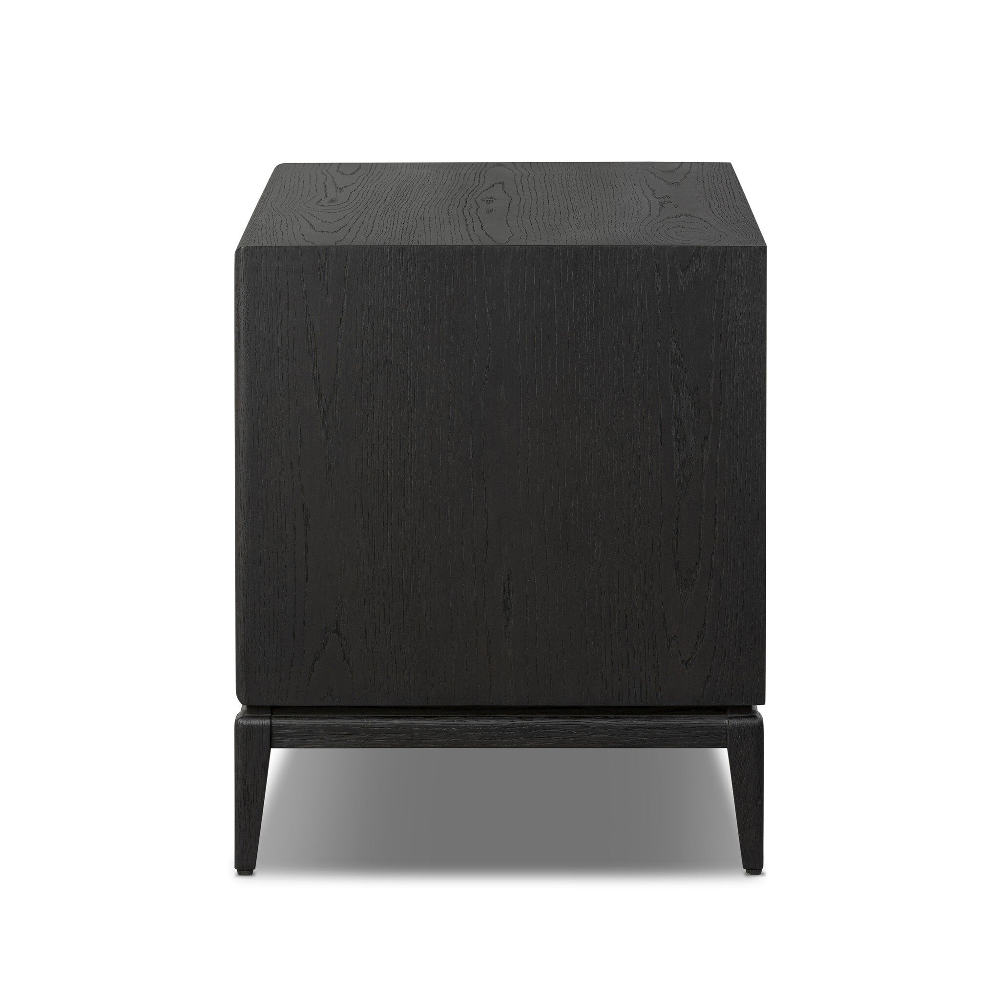 Side profile of a black-finished oak nightstand with a smooth top and single drawer front of woven paper on a white background. 