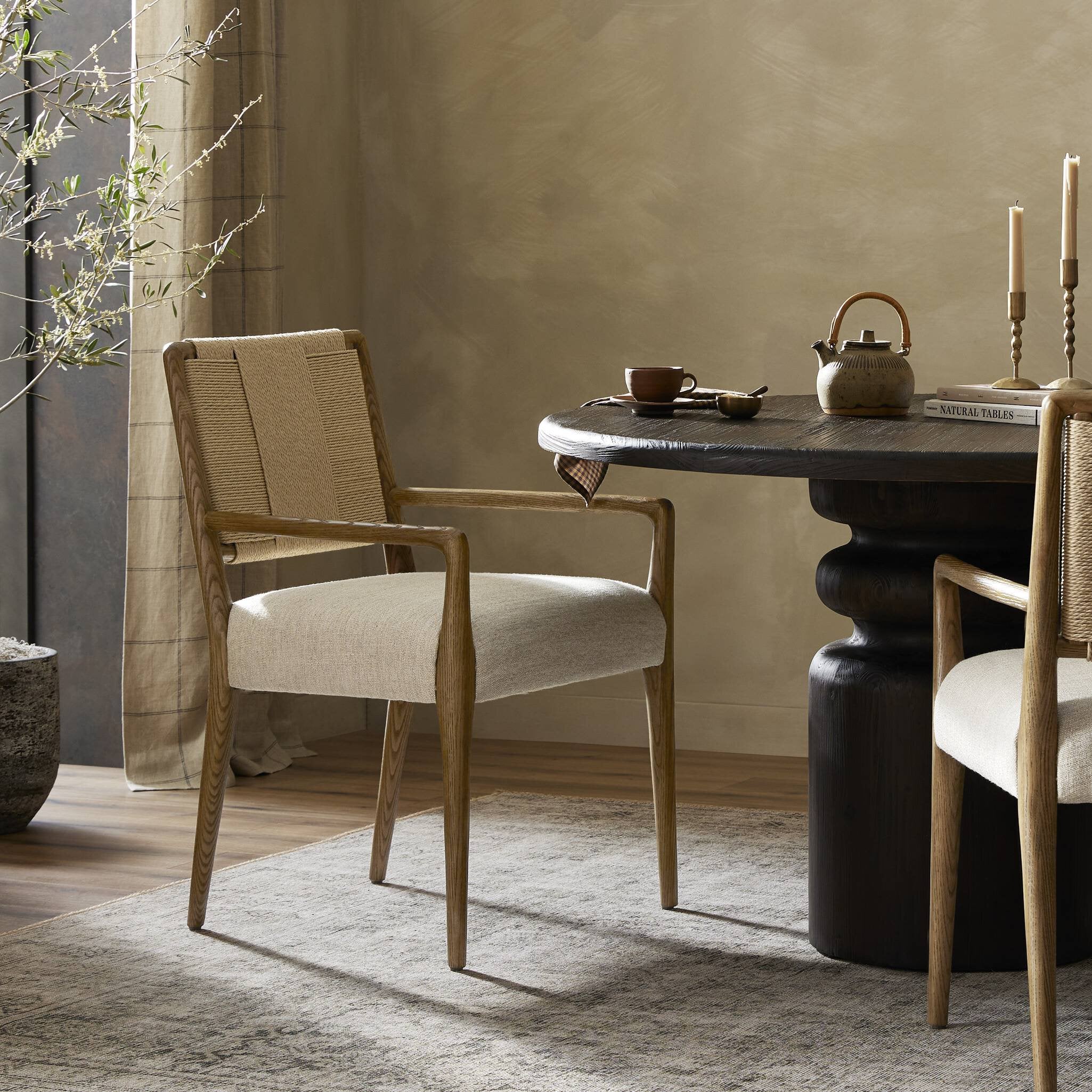 Dining room with a dark wooden table and beige chairs against a neutral wall.