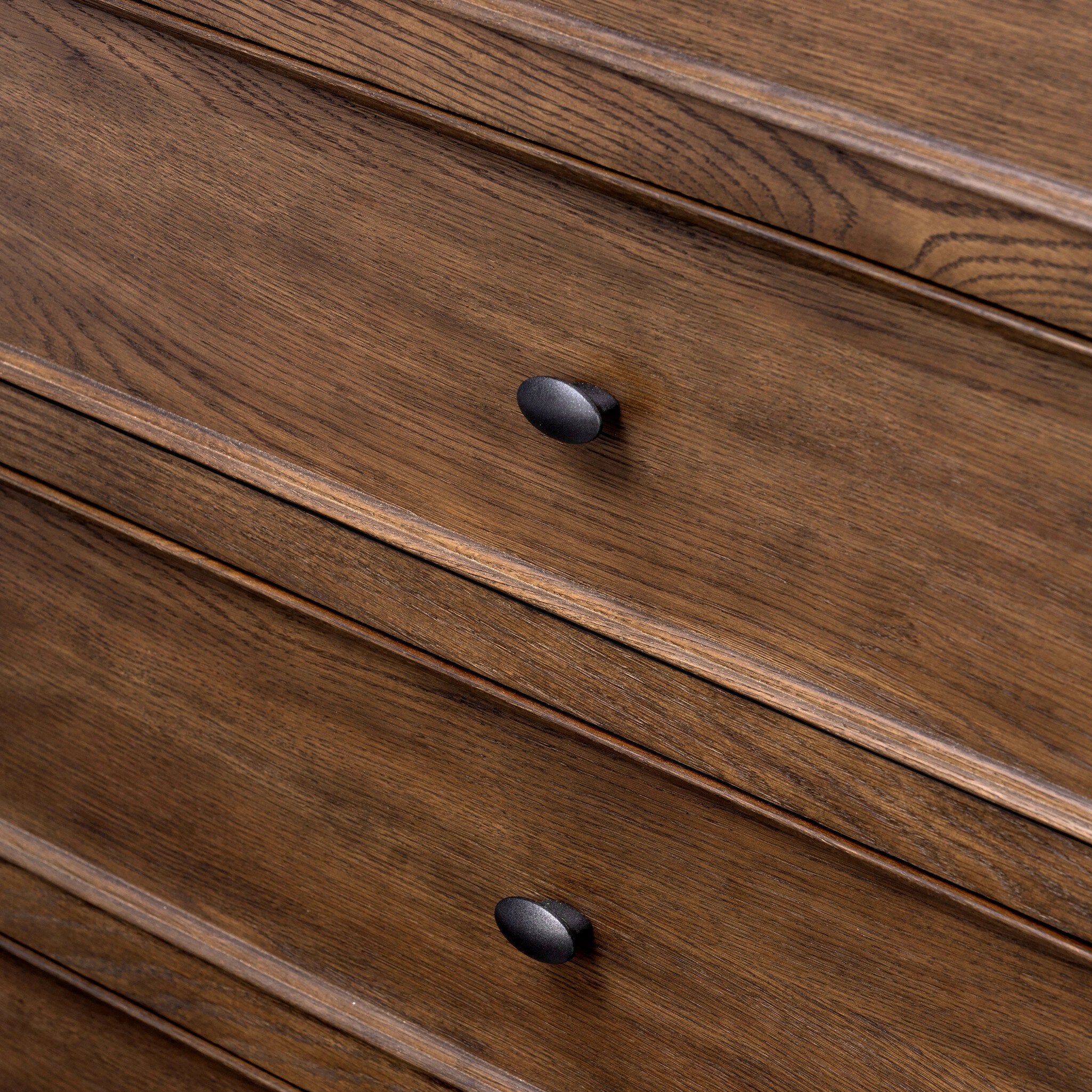 Close up of a wooden dresser with five drawers on a white background.