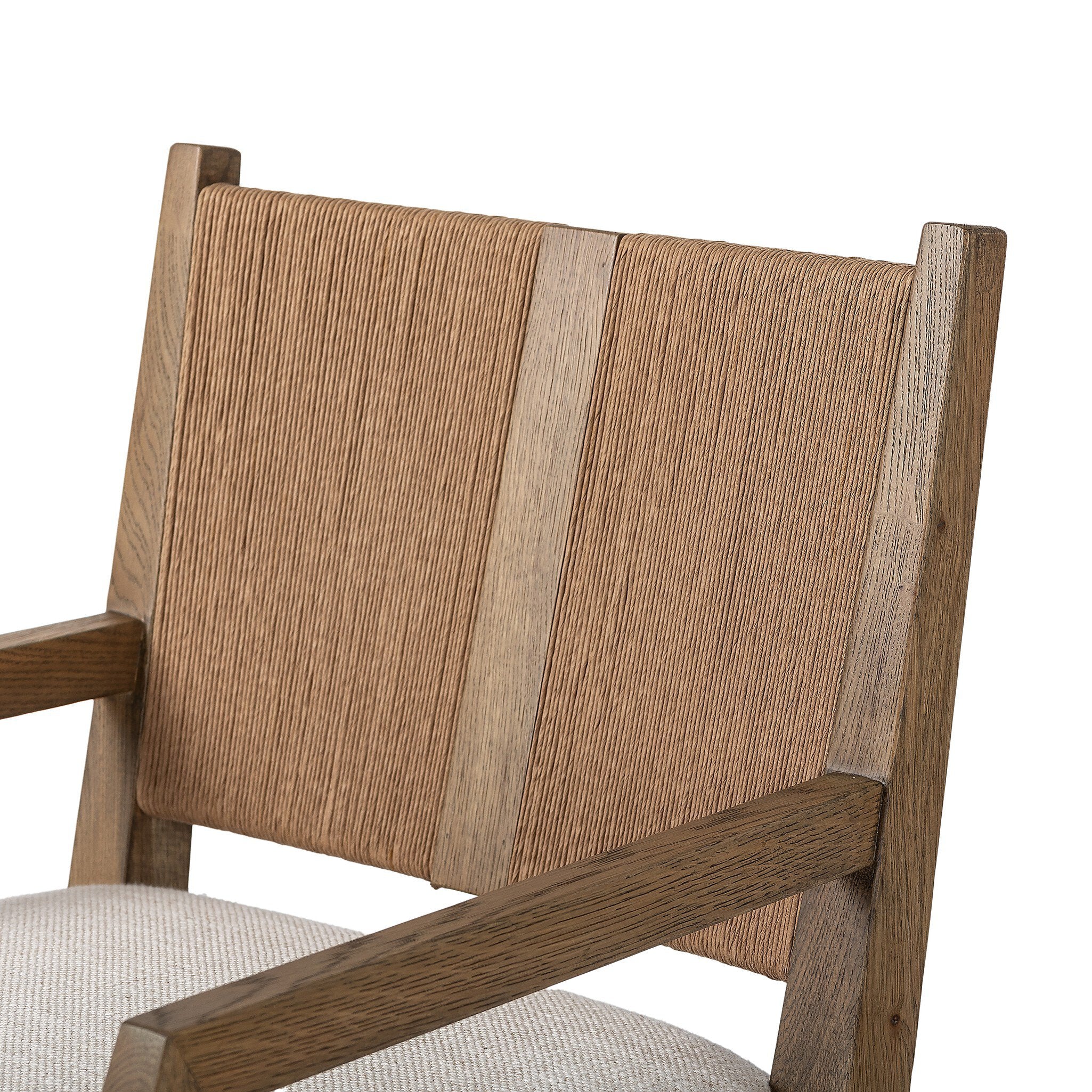 Close up of a wooden dining arm chair with woven backrest and white cushion on a white background.