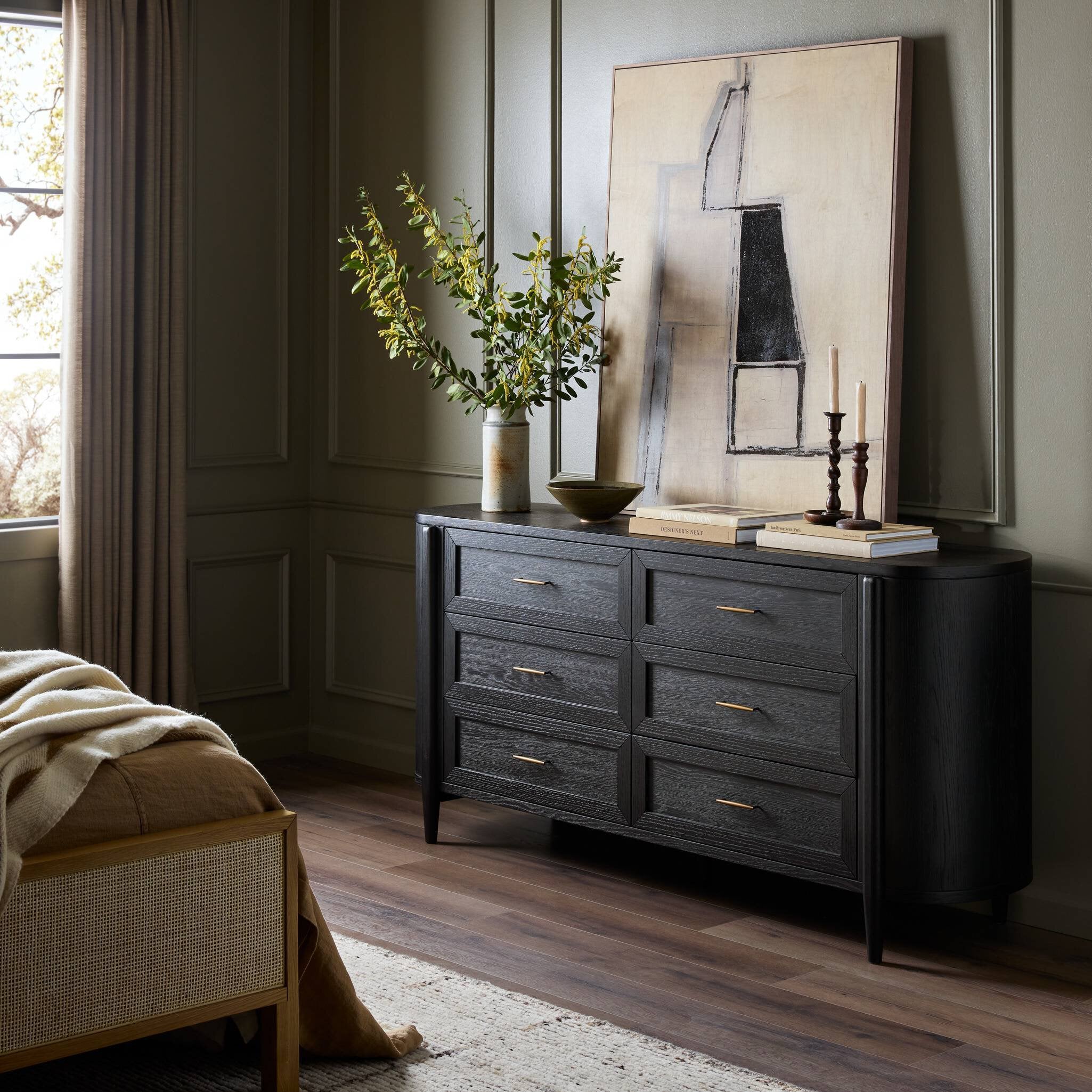 Dark wooden dresser in a room with a painting and plants on top.