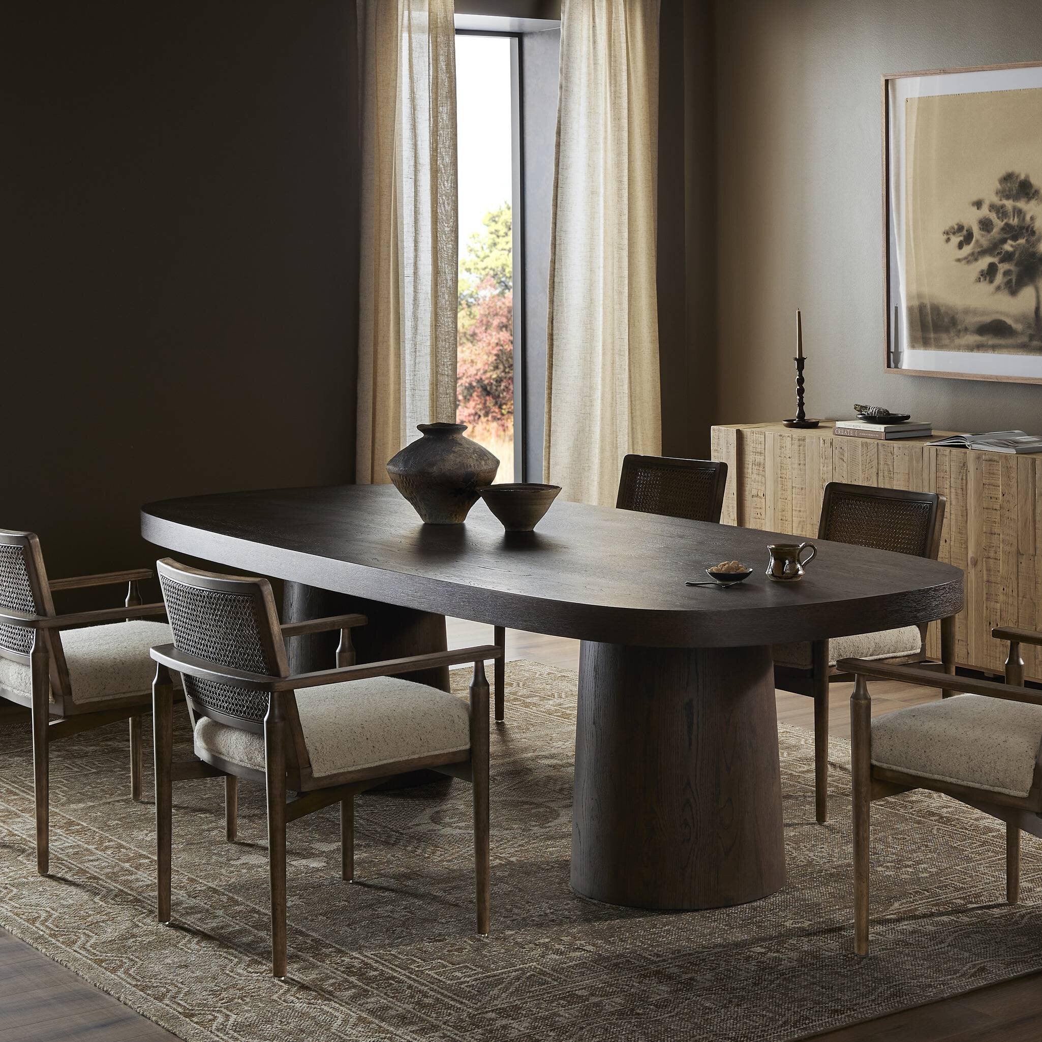 Dining room with a dark wooden table and chairs in a well-lit room.
