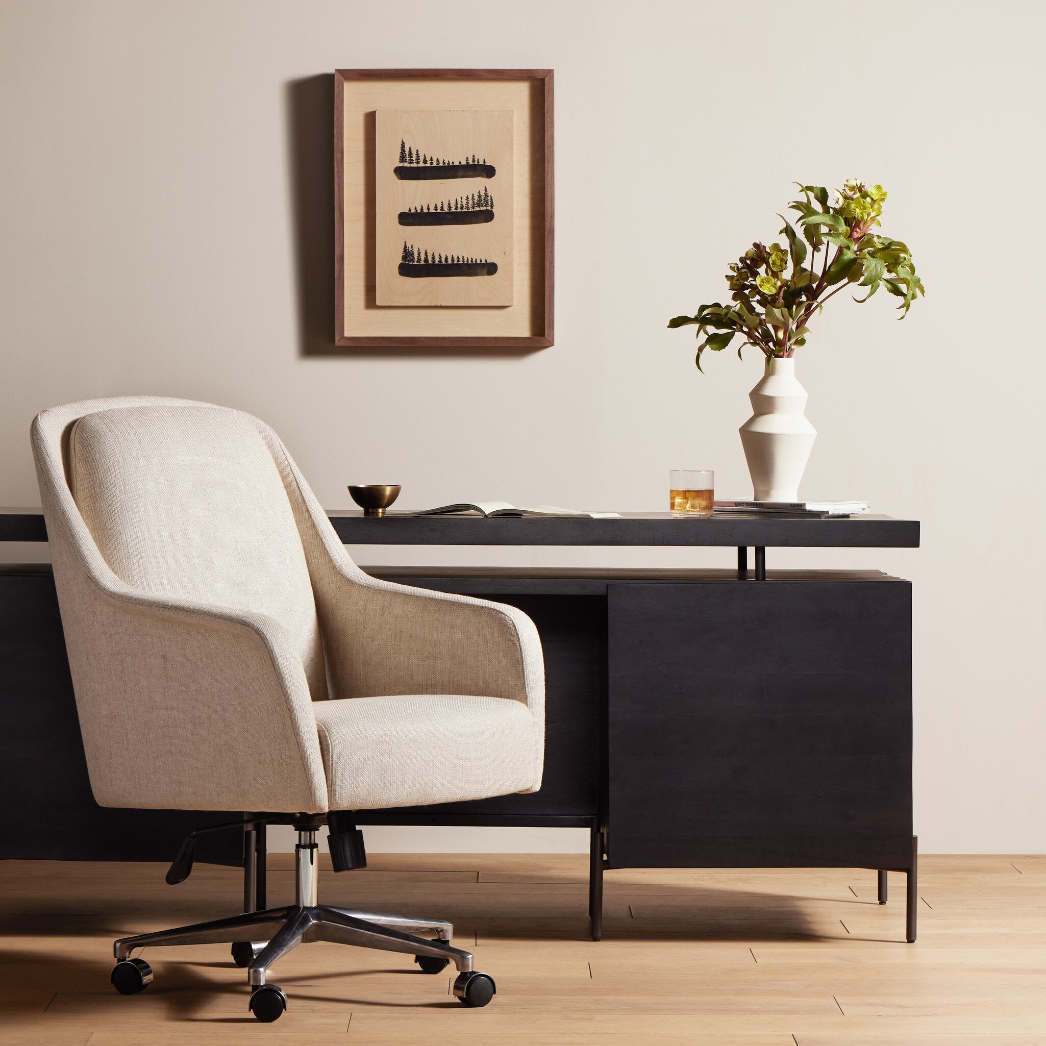 Modern office desk with chair, framed artwork, and decorative items.