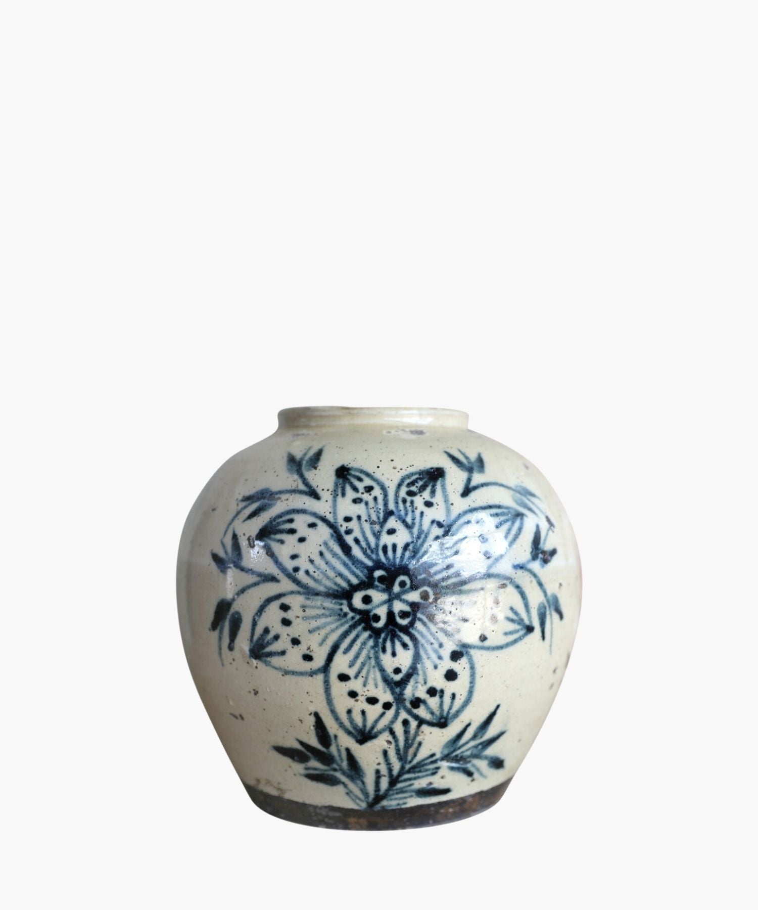A cream toned vintage vase features a large, intricate blue floral design with leaves. The style is traditional, conveying a rustic and artistic feel.