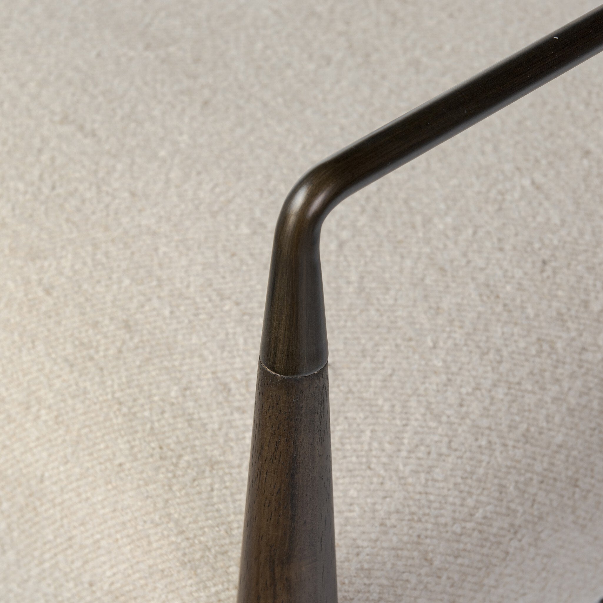 Close up of a beige counter stool with wooden frame on a white background.