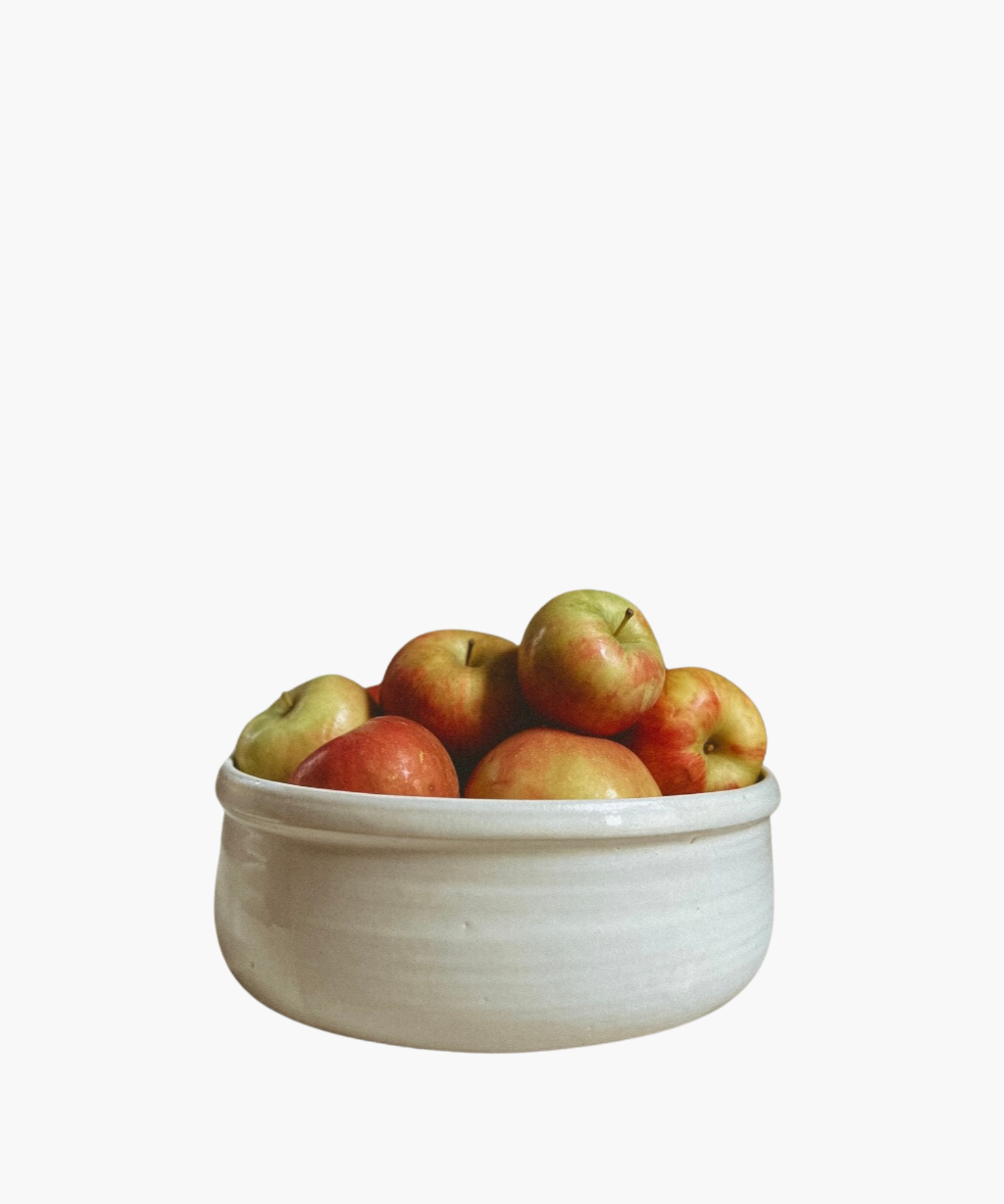 A white ceramic bowl brimming with ripe red and green apples sits against a plain background, conveying a sense of freshness and abundance.