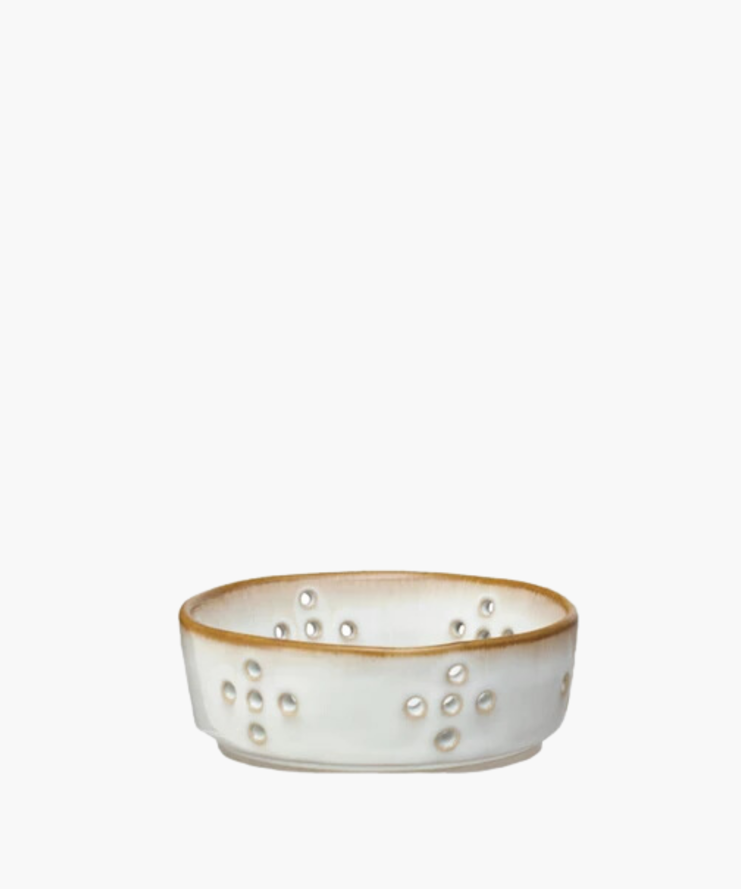 A beige and white ceramic colander features multiple circular drainage holes arranged in patterns. The bowl has a smooth, glazed finish, giving it a rustic appearance.
