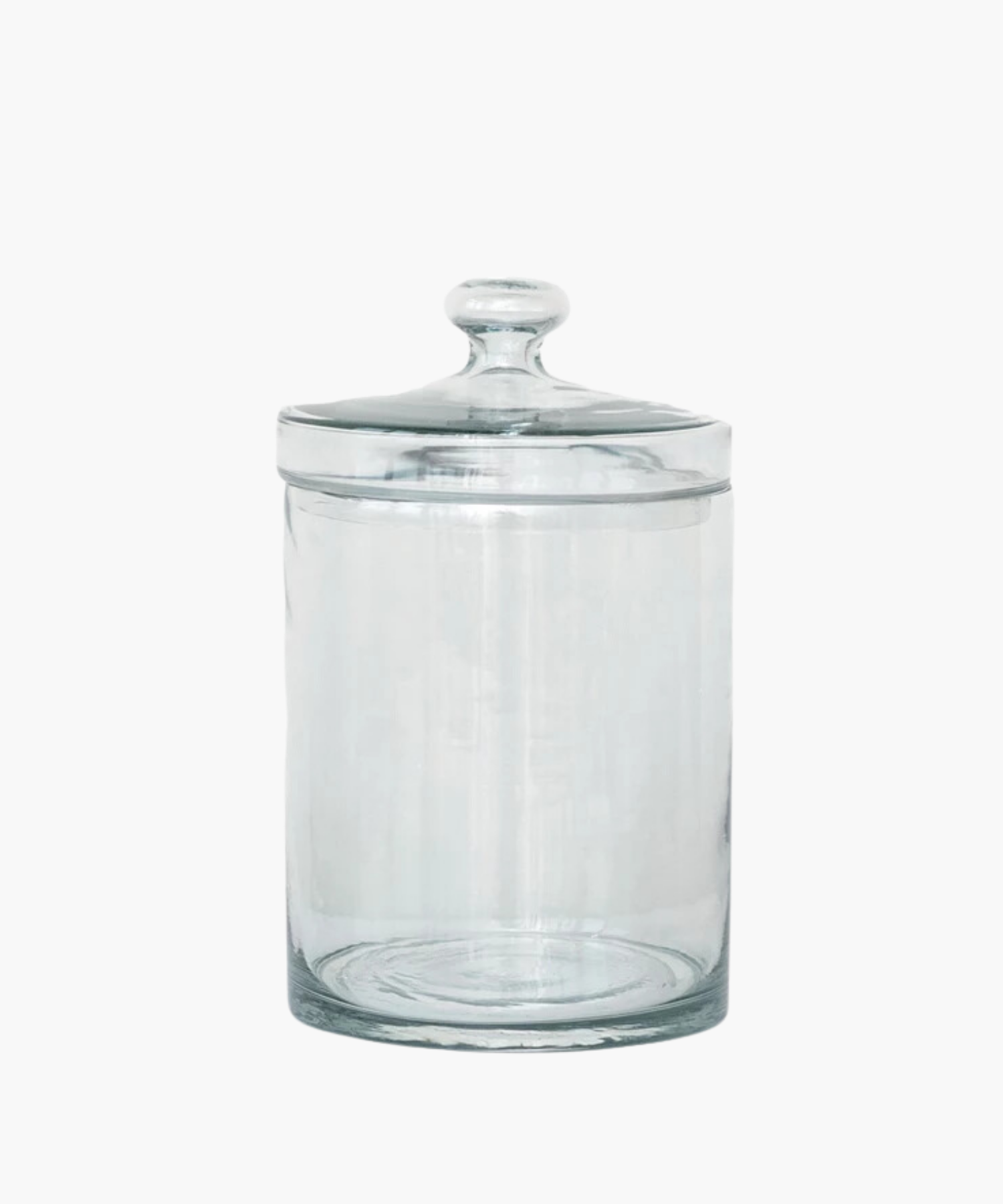 A transparent glass jar with a rounded lid is centered on a white background. The jar is empty and reflects light softly, conveying simplicity and elegance.