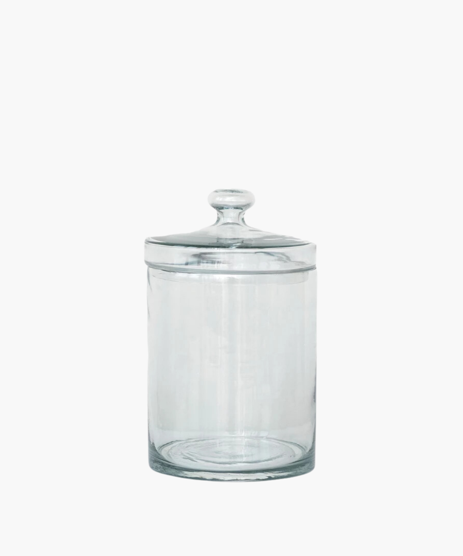 A transparent glass jar with a rounded lid is centered on a white background. The jar is empty and reflects light softly, conveying simplicity and elegance.